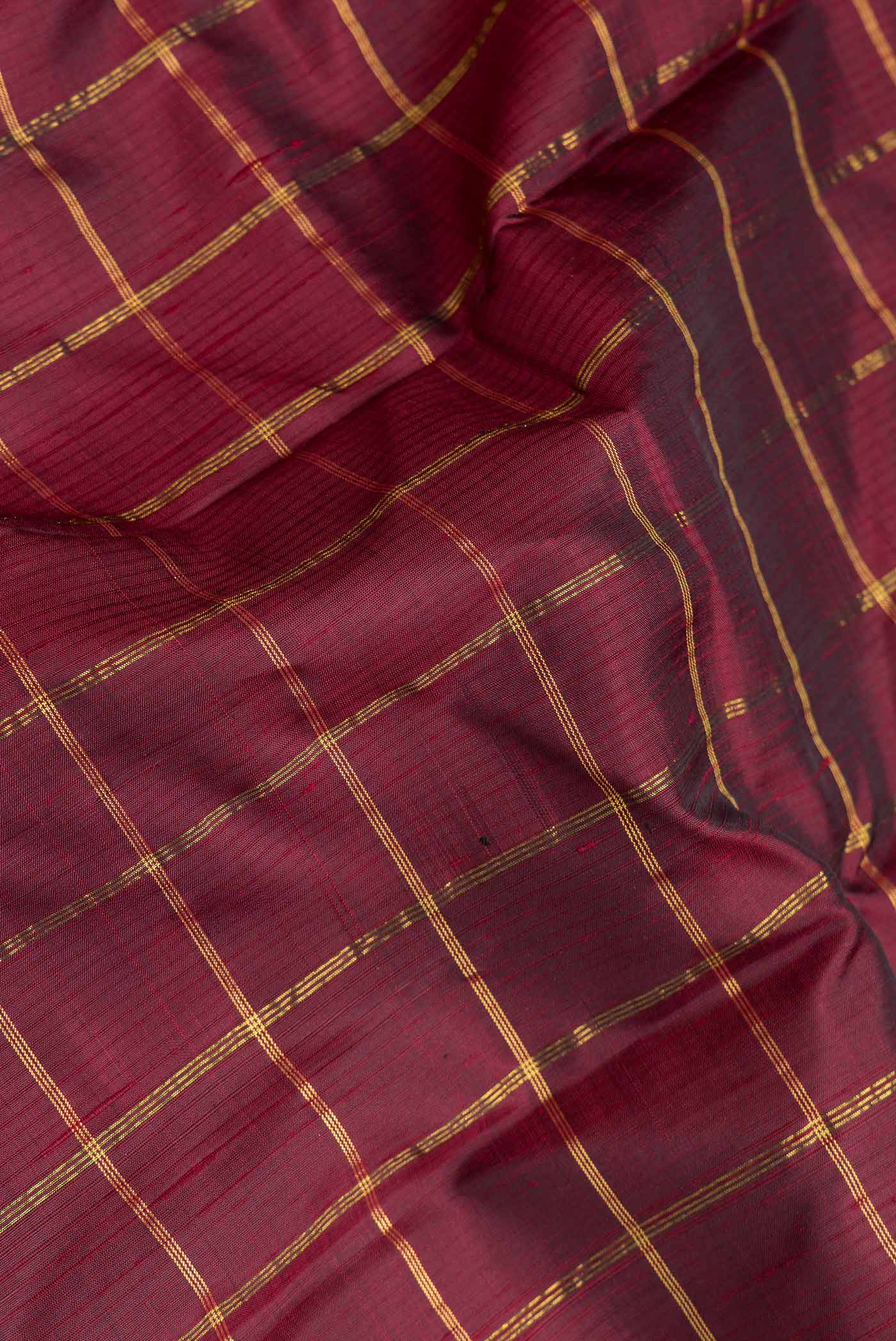 Close up of Maroon Dual Tone Kanchipuram Silk Saree with Checked design on the body and Zari Border.  displaying folds