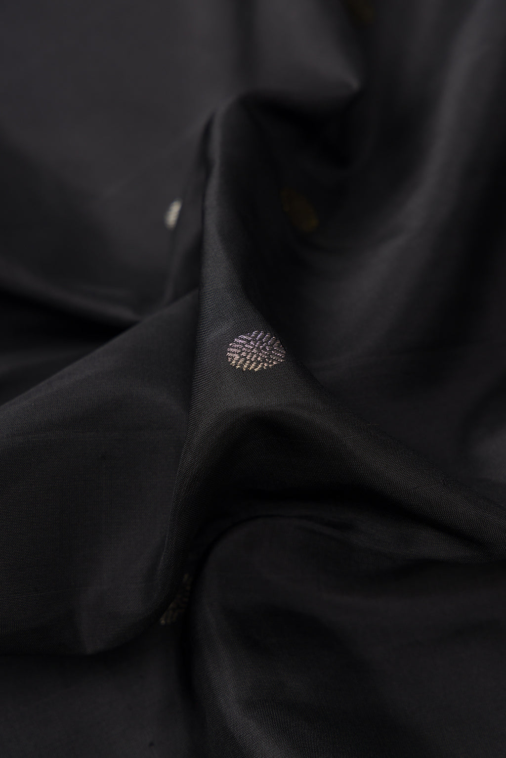 Close up of Black Dual Tone Kanjivaram Silk Saree with Zari Butta on the body and Temple Border.  displaying folds
