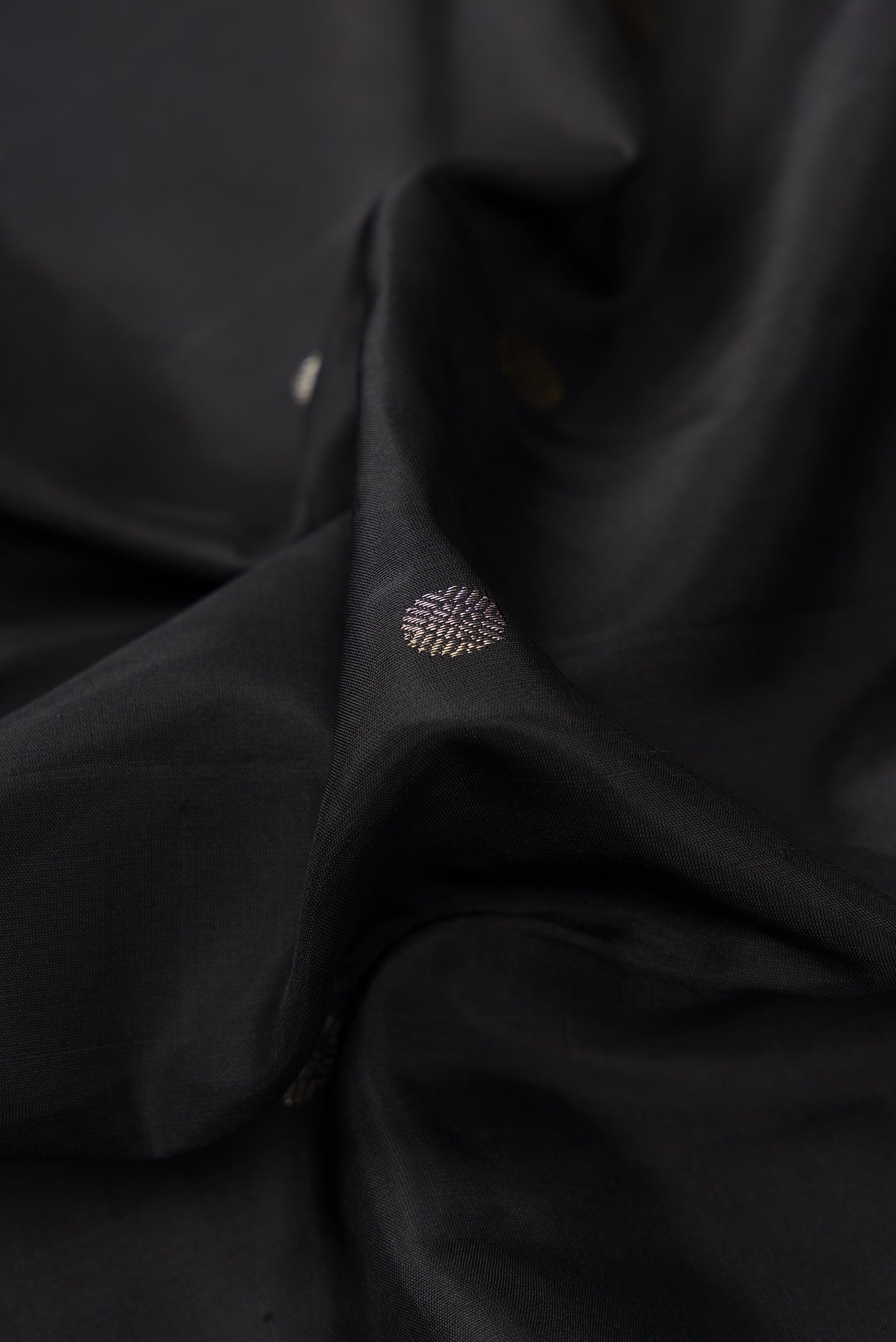 Close up of Black Dual Tone Kanjivaram Silk Saree with Zari Butta on the body and Temple Border.  displaying folds