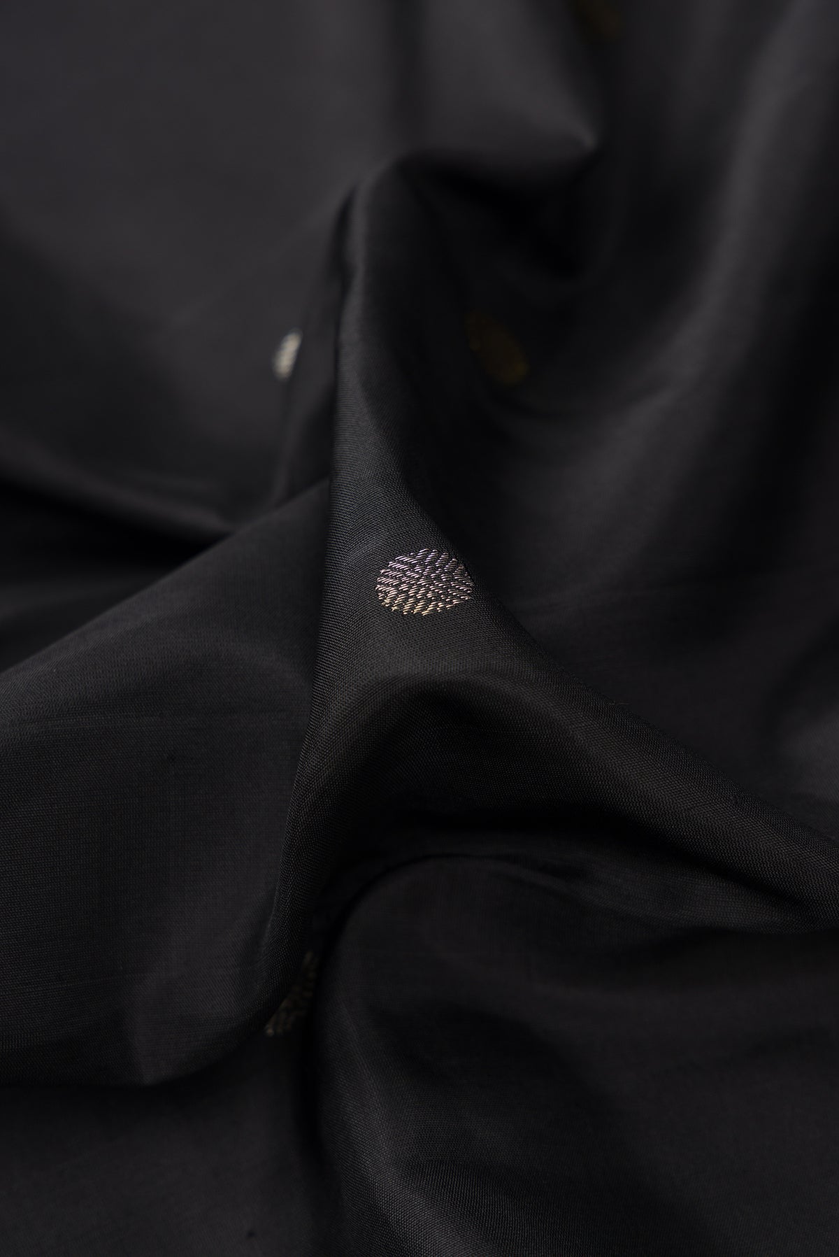 Close up of Black Dual Tone Kanjivaram Silk Saree with Zari Butta on the body and Temple Border.  displaying folds