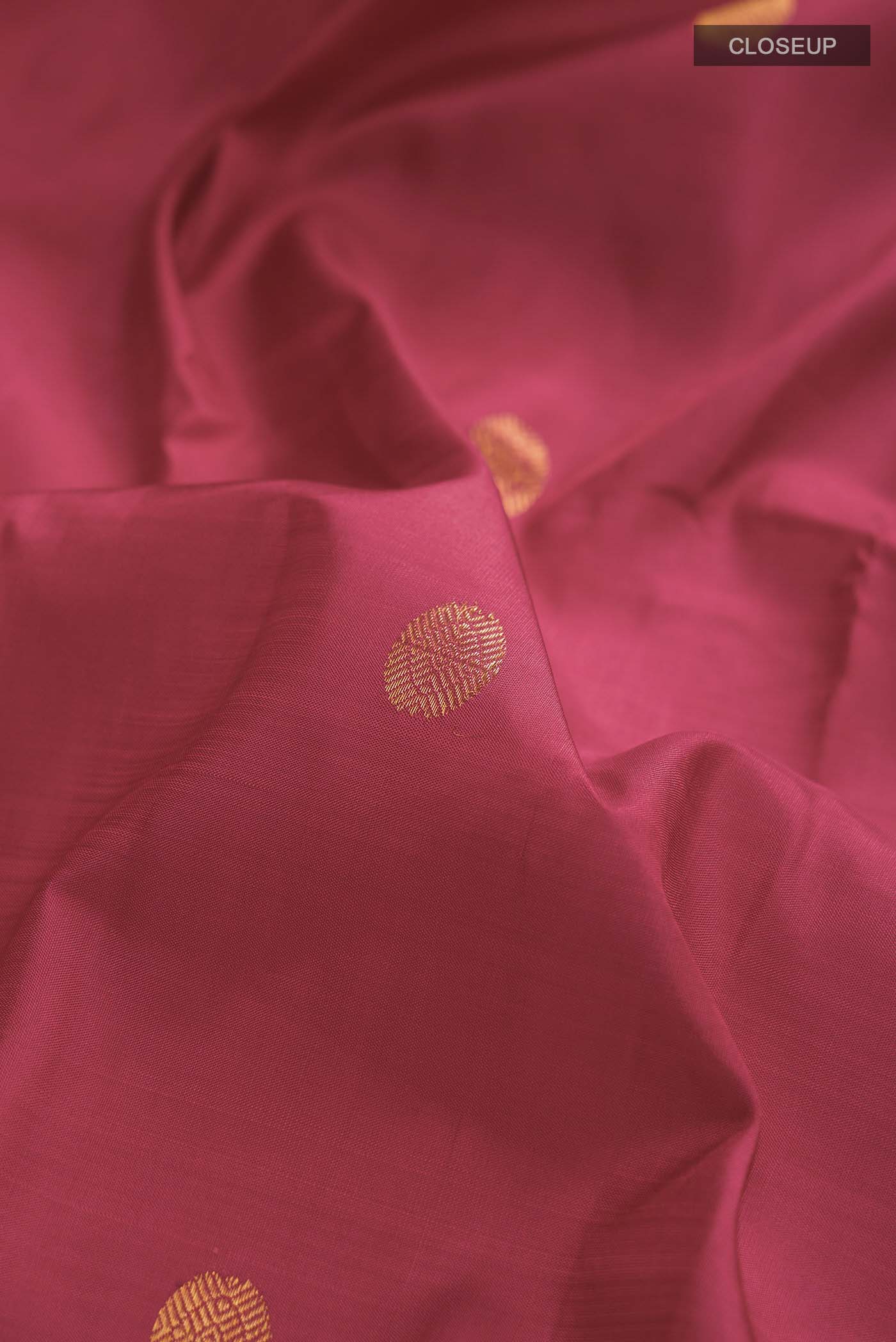 Close up of Pink Kanchipuram Silk Saree with Zari Butta on the body and Zari Border displaying folds