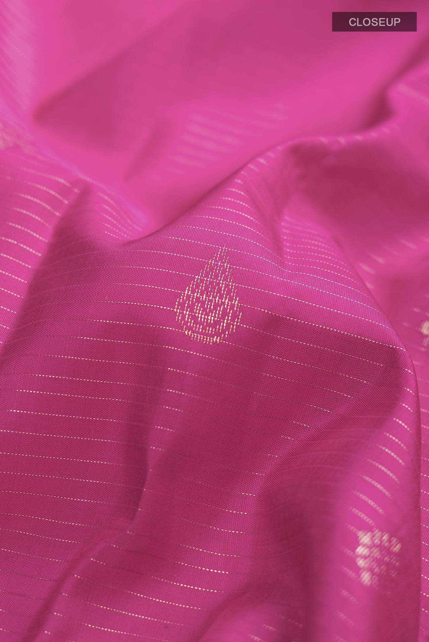 Close up of Pink Kanchipuram Silk Saree with Zari Butta on the body and Zari Border displaying folds