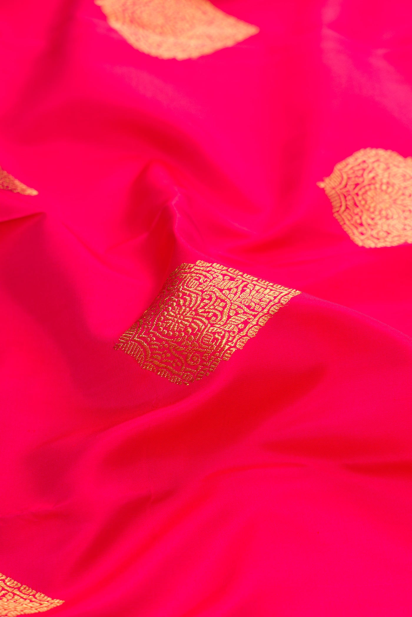 Close up of Pure Silk Pure Zari Pink Kanjivaram Saree with Zari Butta on the body and Zari Border.  displaying folds
