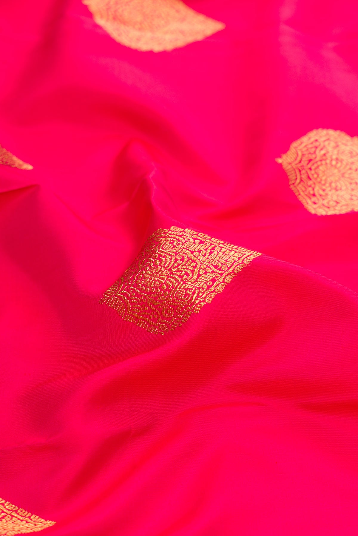 Close up of Pure Silk Pure Zari Pink Kanjivaram Saree with Zari Butta on the body and Zari Border.  displaying folds