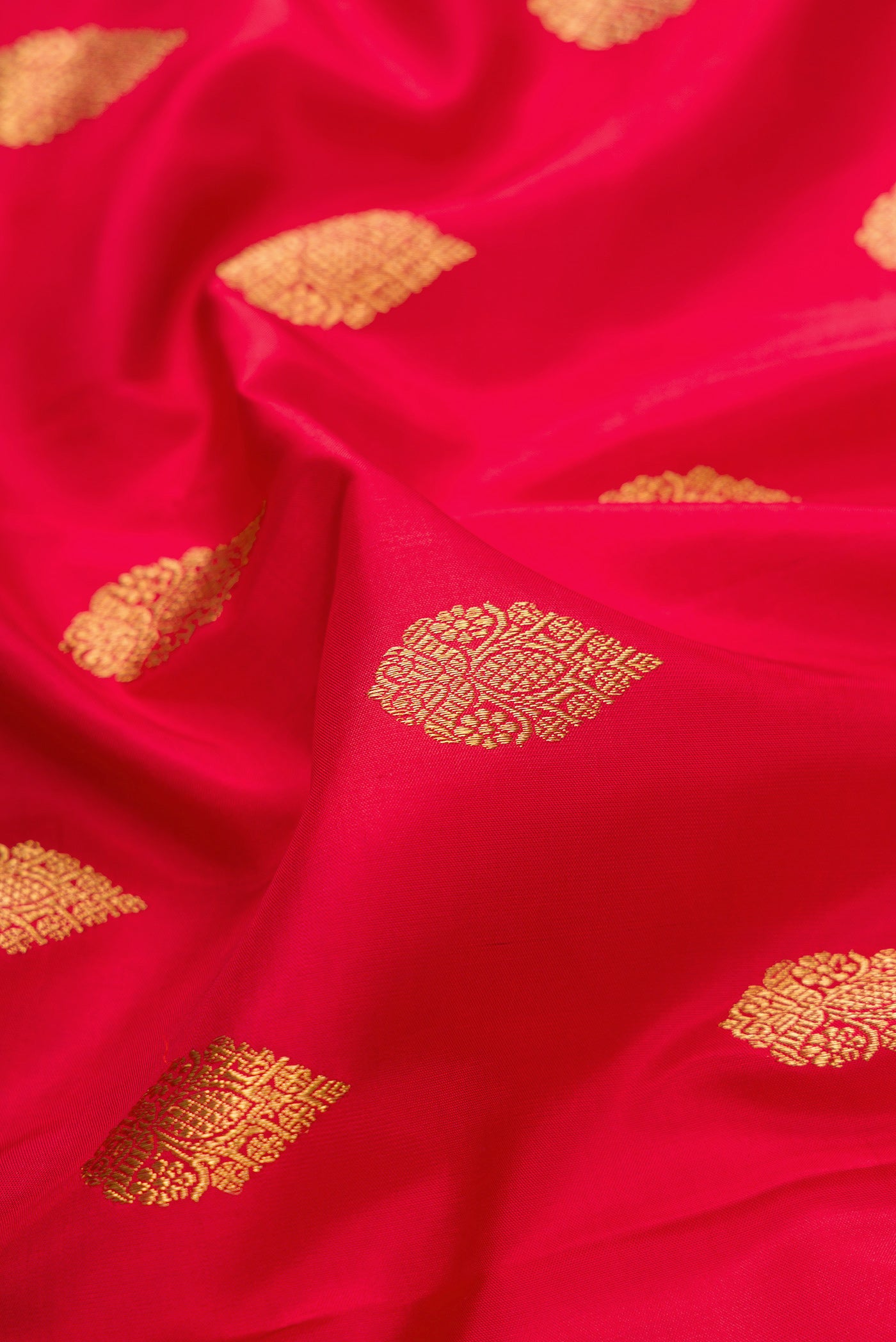 Close up of Pure Silk Pure Zari Red Dual Tone Kanjivaram Saree with Zari Butta on the body and Zari Border.  displaying folds