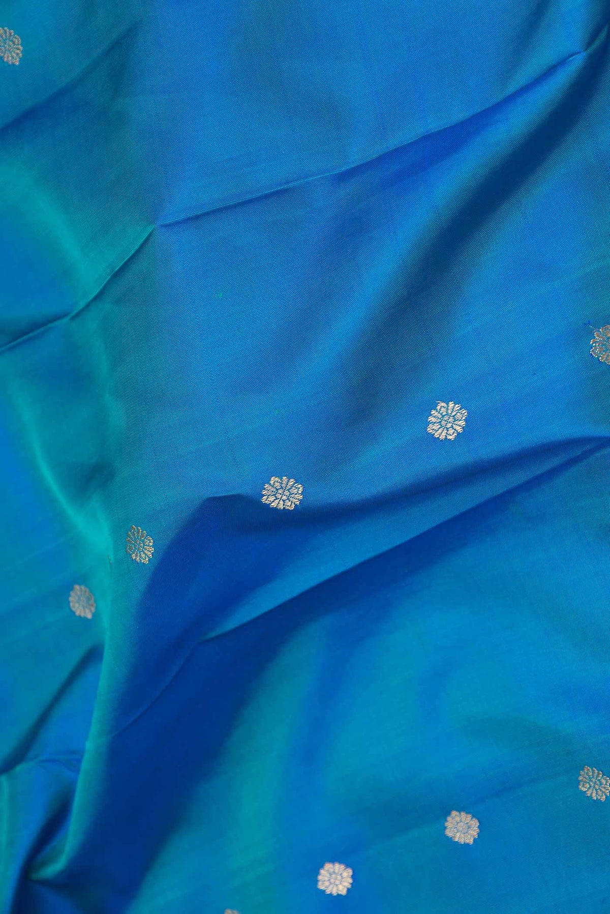 Close up of Pure Silk Pure Zari Peacock Blue Dual Tone Kanchipuram Saree with Zari Butta on the body and Zari Border displaying folds