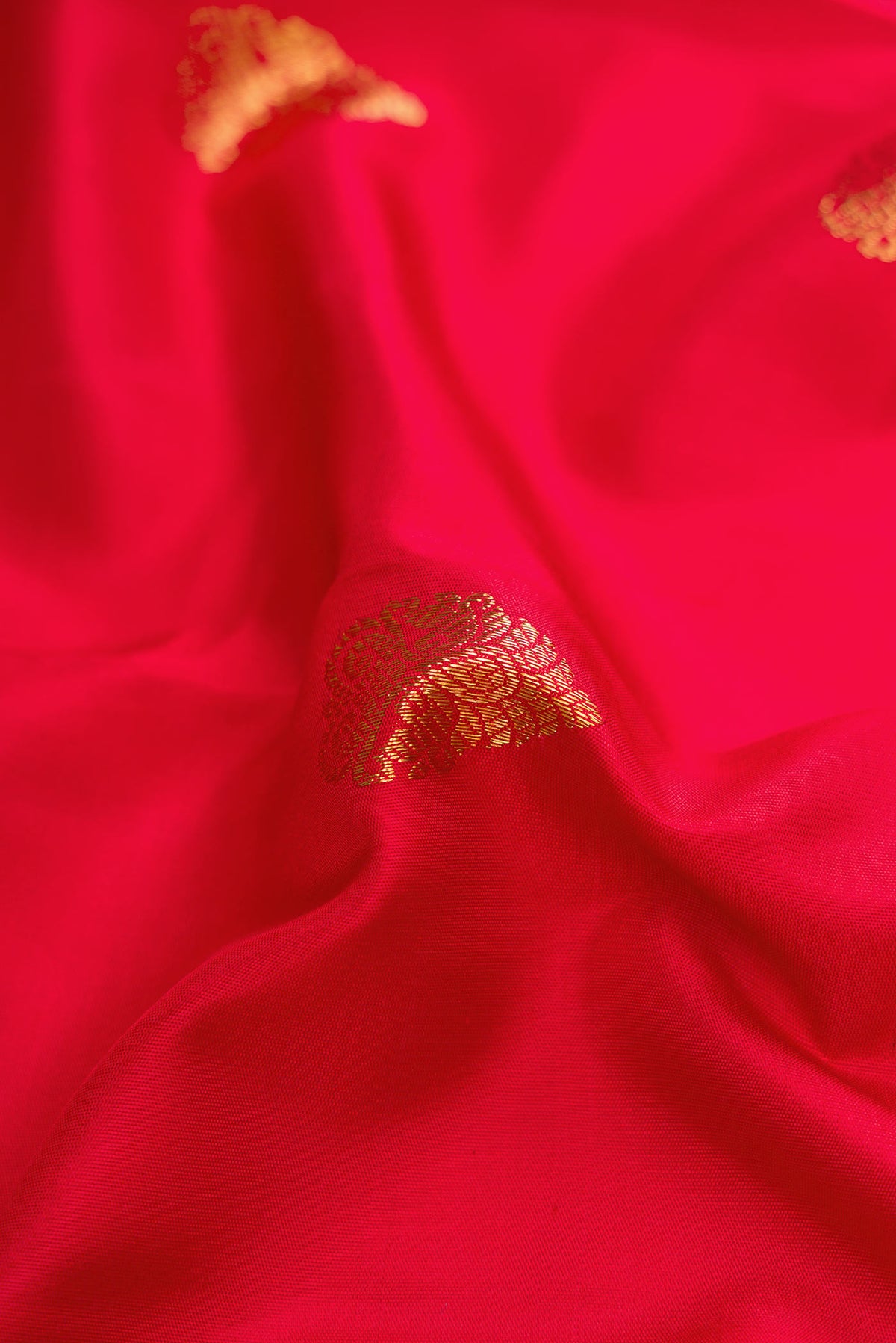 Close up of Pure Silk Pure Zari Red Dual Tone Kanchipuram Saree with Zari Butta on the body and Zari Border displaying folds