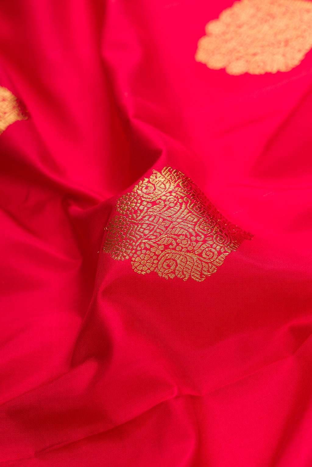 Close up of Pure Silk Pure Zari Red Dual Tone Kanjivaram Saree with Zari Butta on the body and Fancy Border.  displaying folds