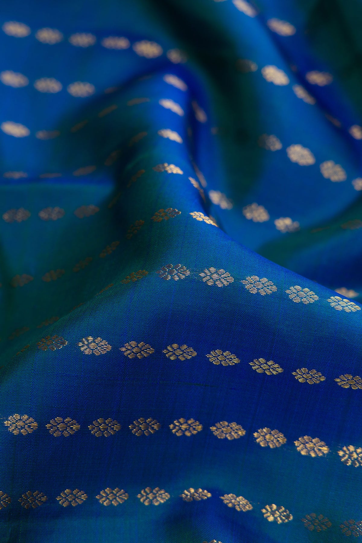 Close up of Pure Silk Pure Zari Peacock Blue Dual Tone Kanjivaram Saree with Zari Butta on the body and Zari Border.  displaying folds