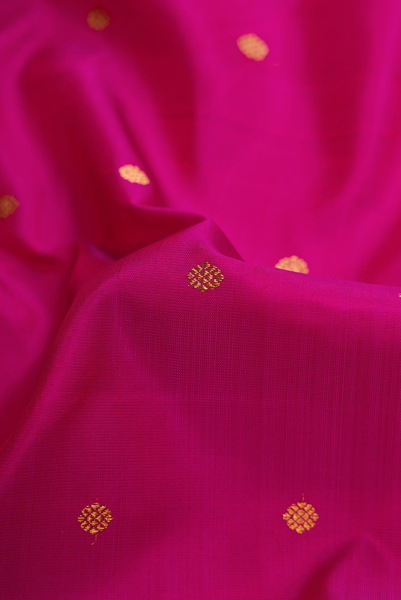 Close up of Pure Silk Pure Zari Magenta Dual Tone Kanchipuram Saree with Zari Butta on the body and Zari Border displaying folds