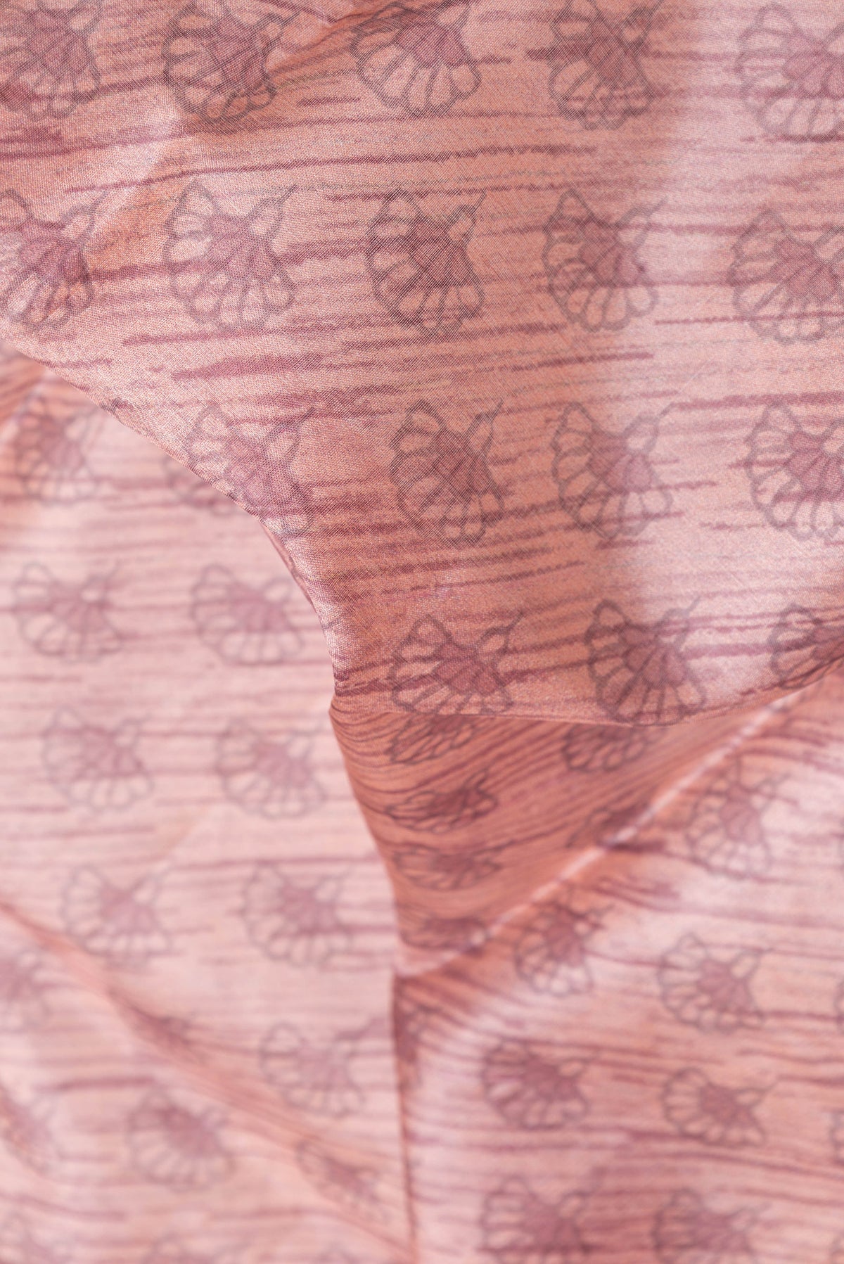 Close up of Golden Peach Dual Tone Tussar Silk Saree with Printed design on the body and Zari Border.  displaying folds