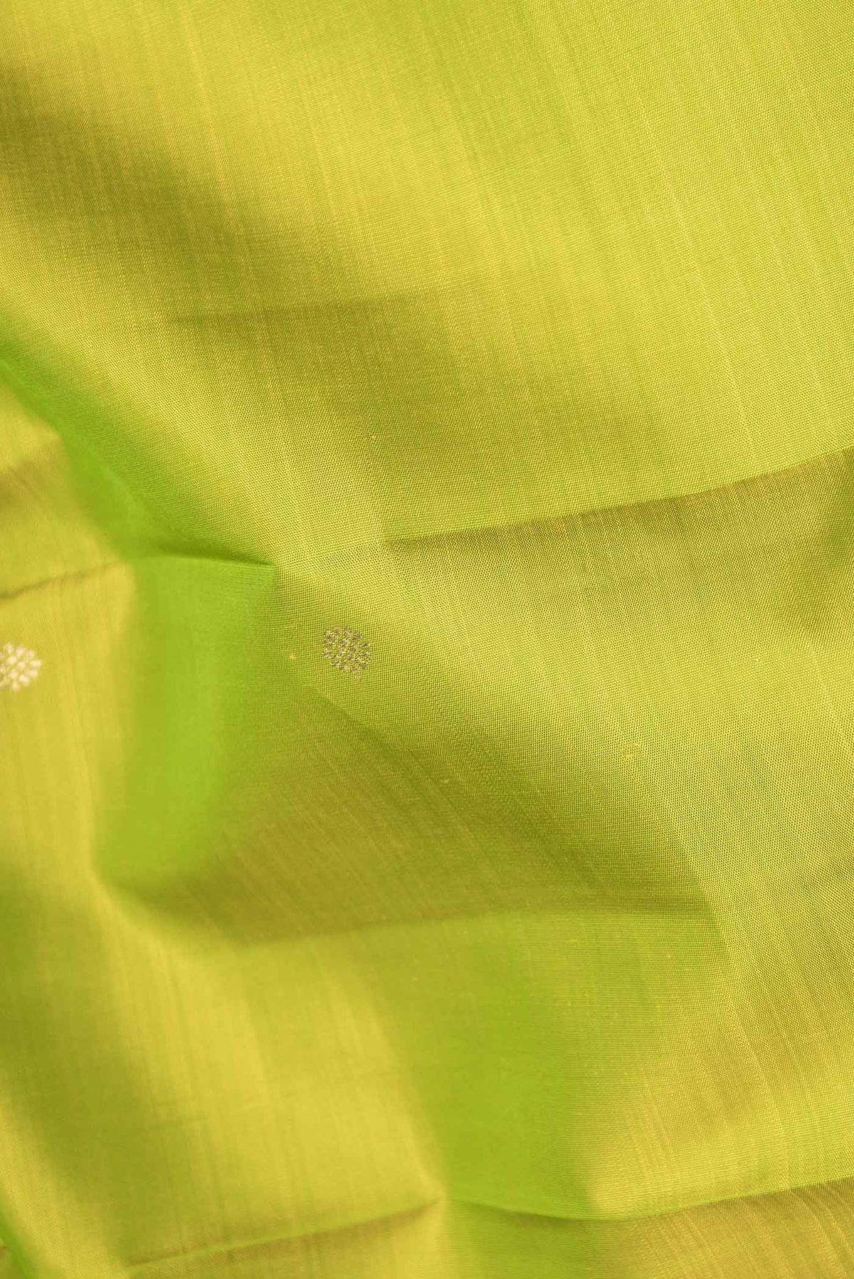 Close up of Pure Silk Pure Zari Parrot Green Dual Tone Kanchipuram Saree with Zari Butta on the body and Zari Border displaying folds