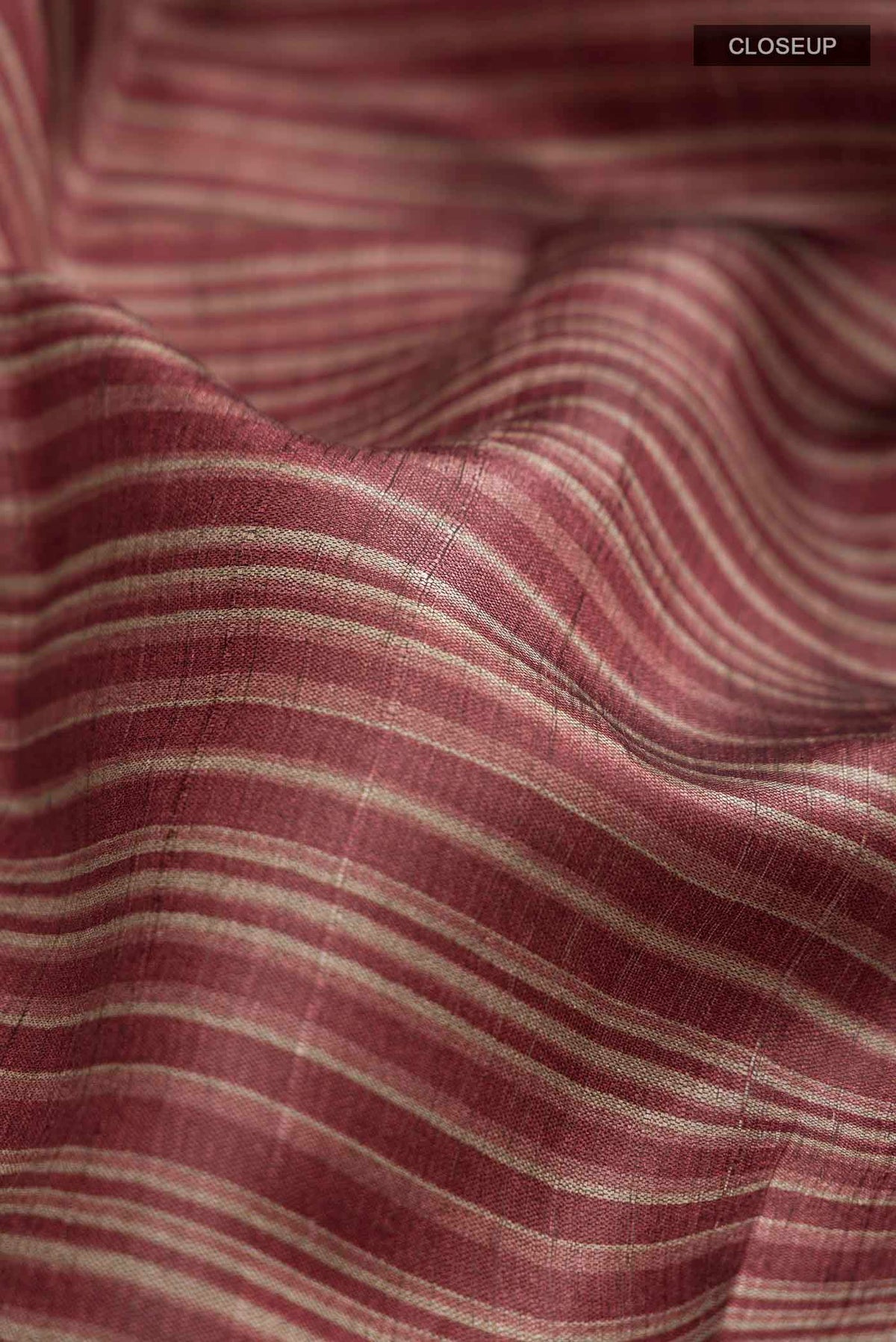 Close up of Maroon Bhagalpuri Tussar Silk Saree with Stripes on the body and Zari Border displaying folds