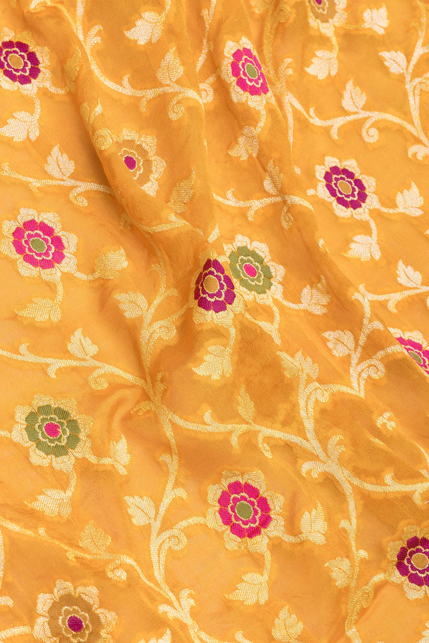 Close up of Mustard Banarasi Georgette Saree with Zari Brocade on the body and Zari And Thread Border.  displaying folds