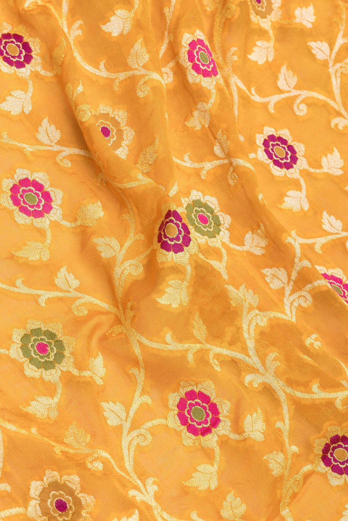 Close up of Mustard Banarasi Georgette Saree with Zari Brocade on the body and Zari And Thread Border.  displaying folds