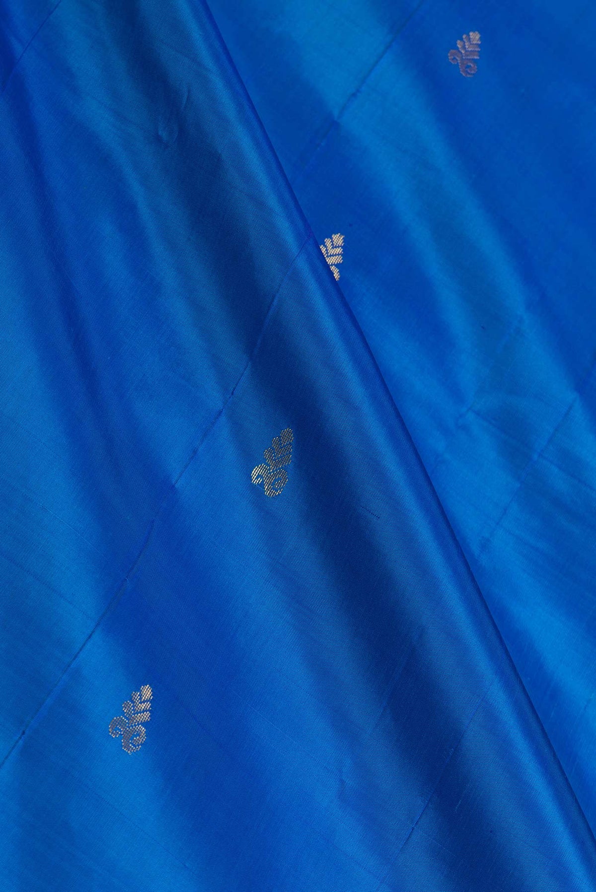 Close up of Peacock Blue Dual Tone Kanchipuram Saree with Zari Butta on the body and Zari Border displaying folds