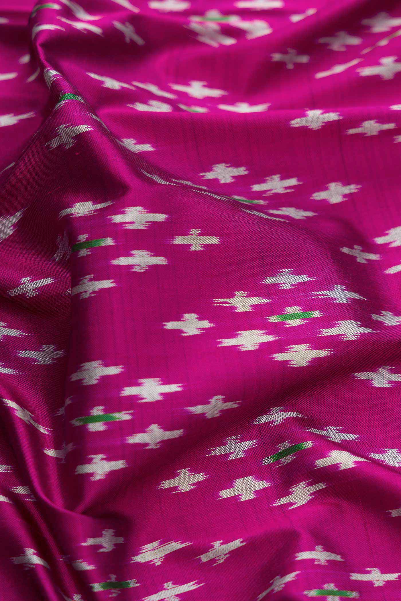 Close up of Magenta Dual Tone Double Ikat Saree with Ikat Print on the body and Ikat Border.  displaying folds