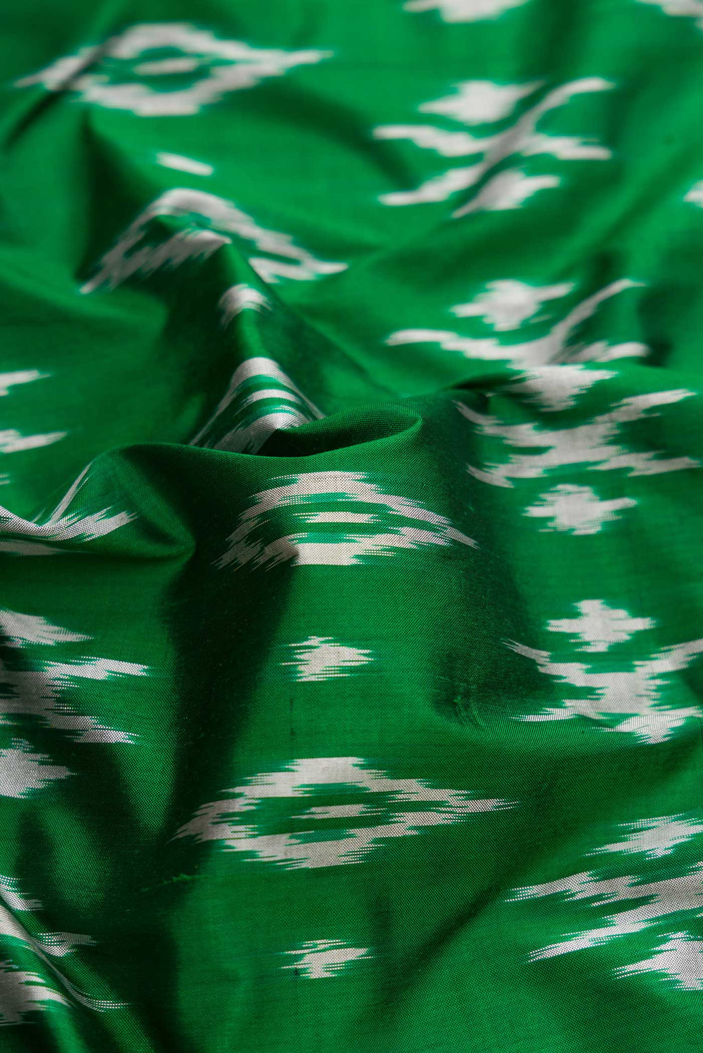 Close up of Green Dual Tone Double Ikat Saree with Ikat Print on the body and Ikat Border.  displaying folds