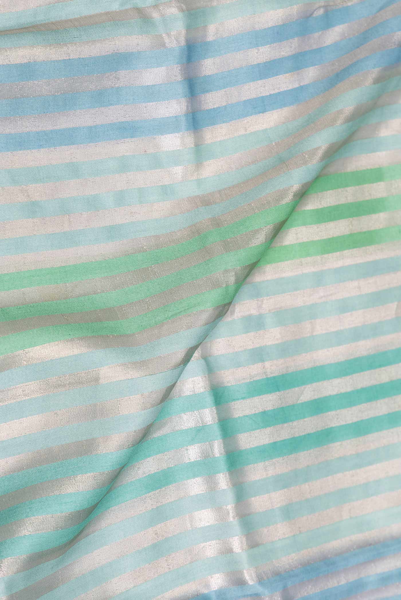 Close up of Sky Blue and Sea Green Color Banarasi Saree with Stripes on the body and Zari Border displaying folds