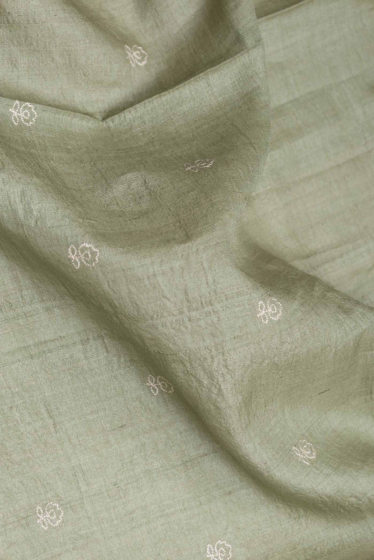 Close up of Sage Green Tussar Silk Saree with Embroidery on the body and Embroidery Border displaying folds