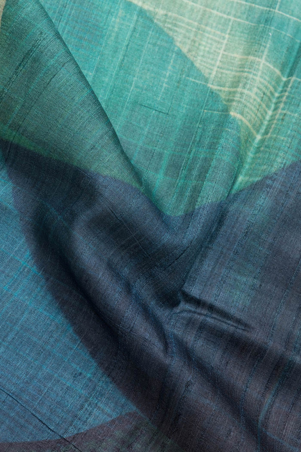 Close up of Mustard and Peakcock Blue Color Tussar Silk Saree with Printed design on the body and Zari Border.  displaying folds