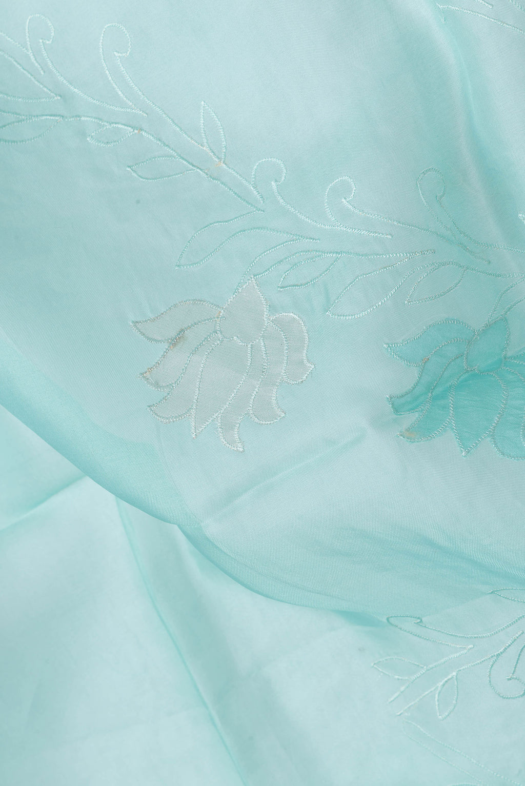 Close up of Sea Green Dual Tone Organza Silk Saree with Embroidery on the body and Embroidery Border.  displaying folds