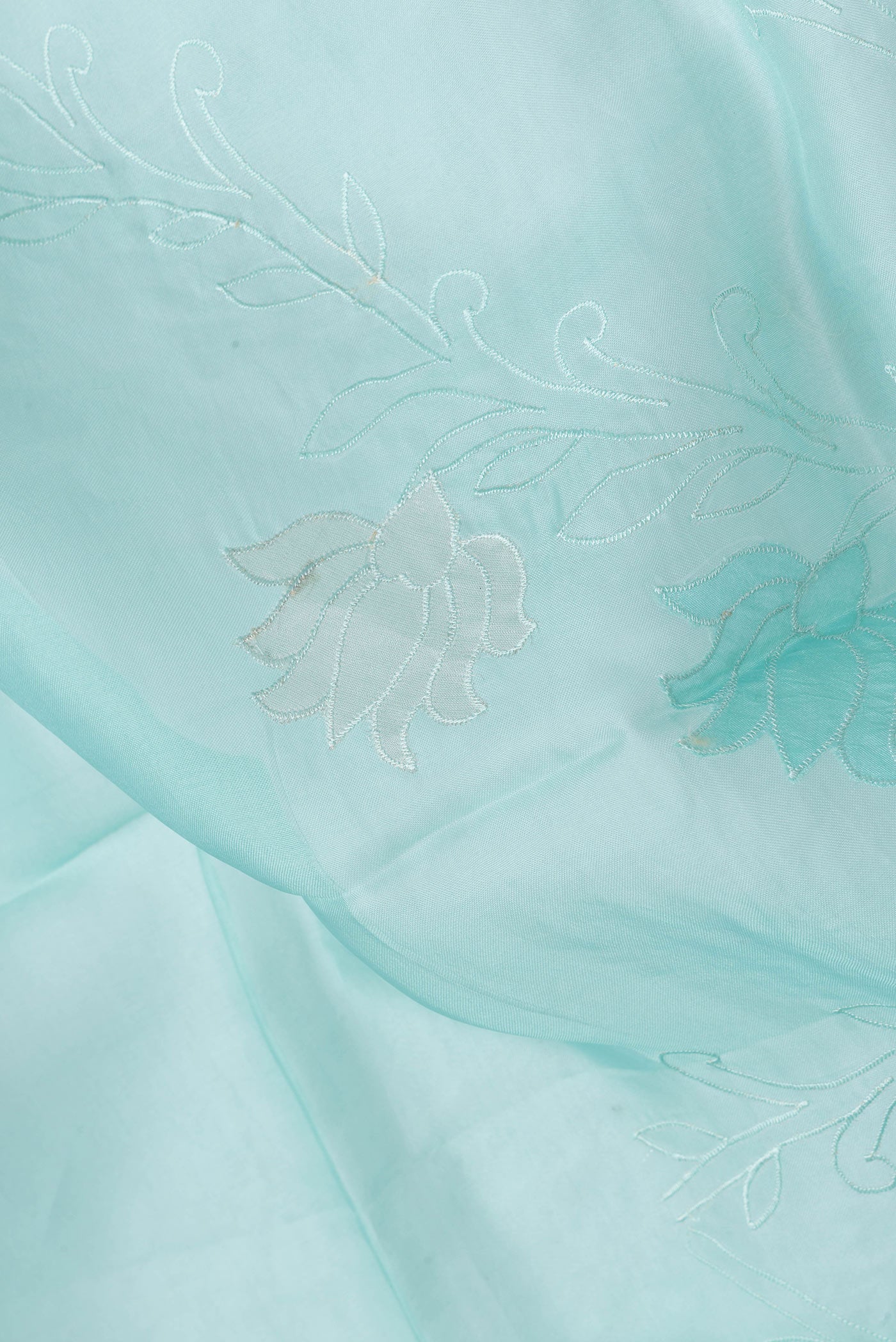 Close up of Sea Green Dual Tone Organza Silk Saree with Embroidery on the body and Embroidery Border.  displaying folds