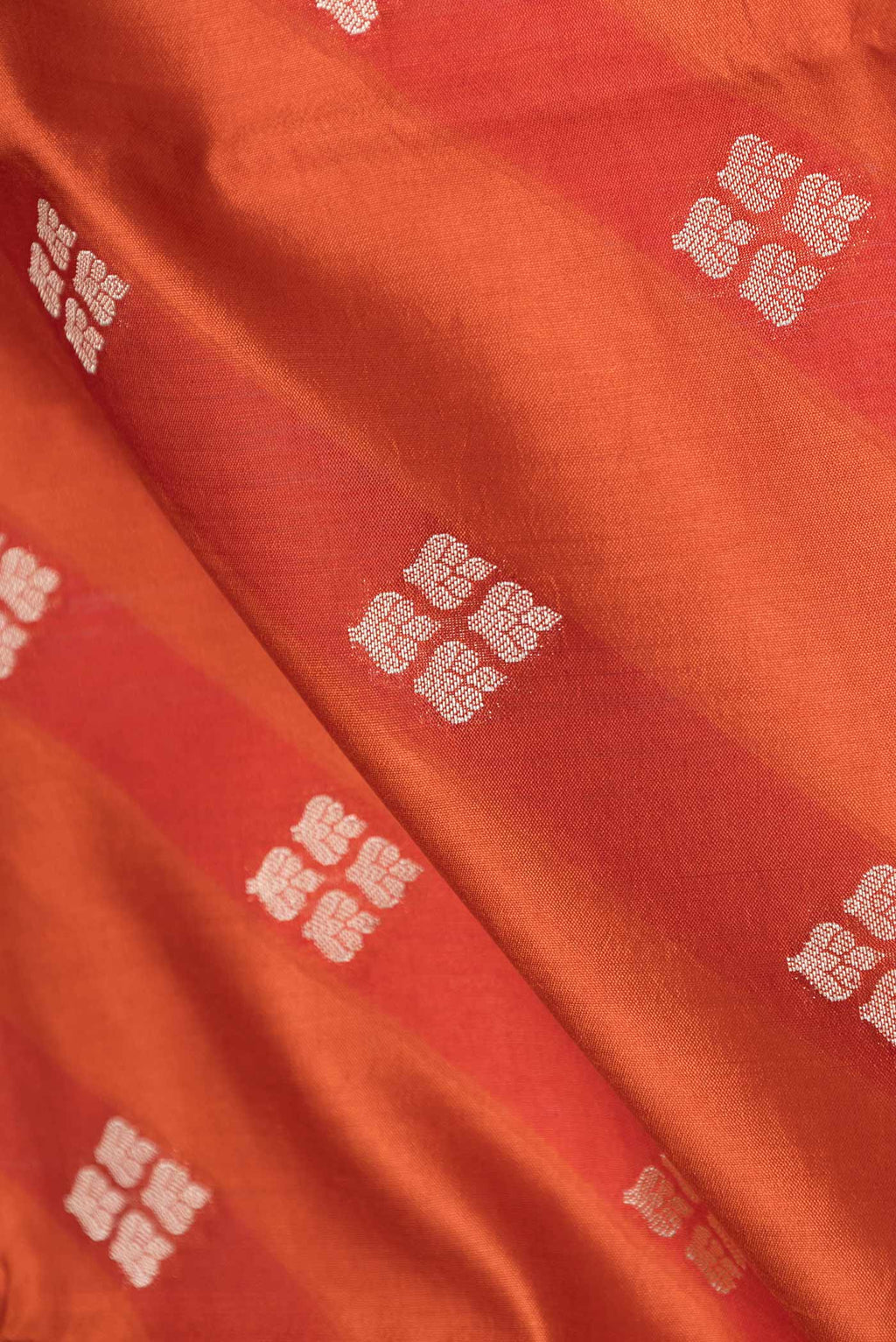 Close up of Orange Banarasi Raw Silk Saree with Zari Butta on the body and Zari Border displaying folds