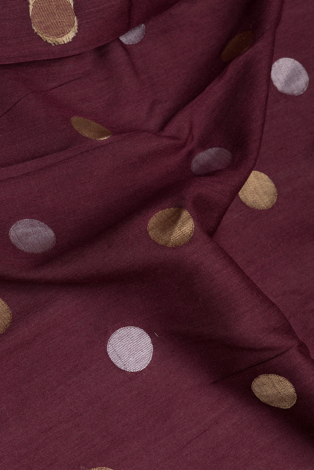 Close up of Burgundy Tussar Silk Saree with Polka Dots on the body and Zari Border.  displaying folds