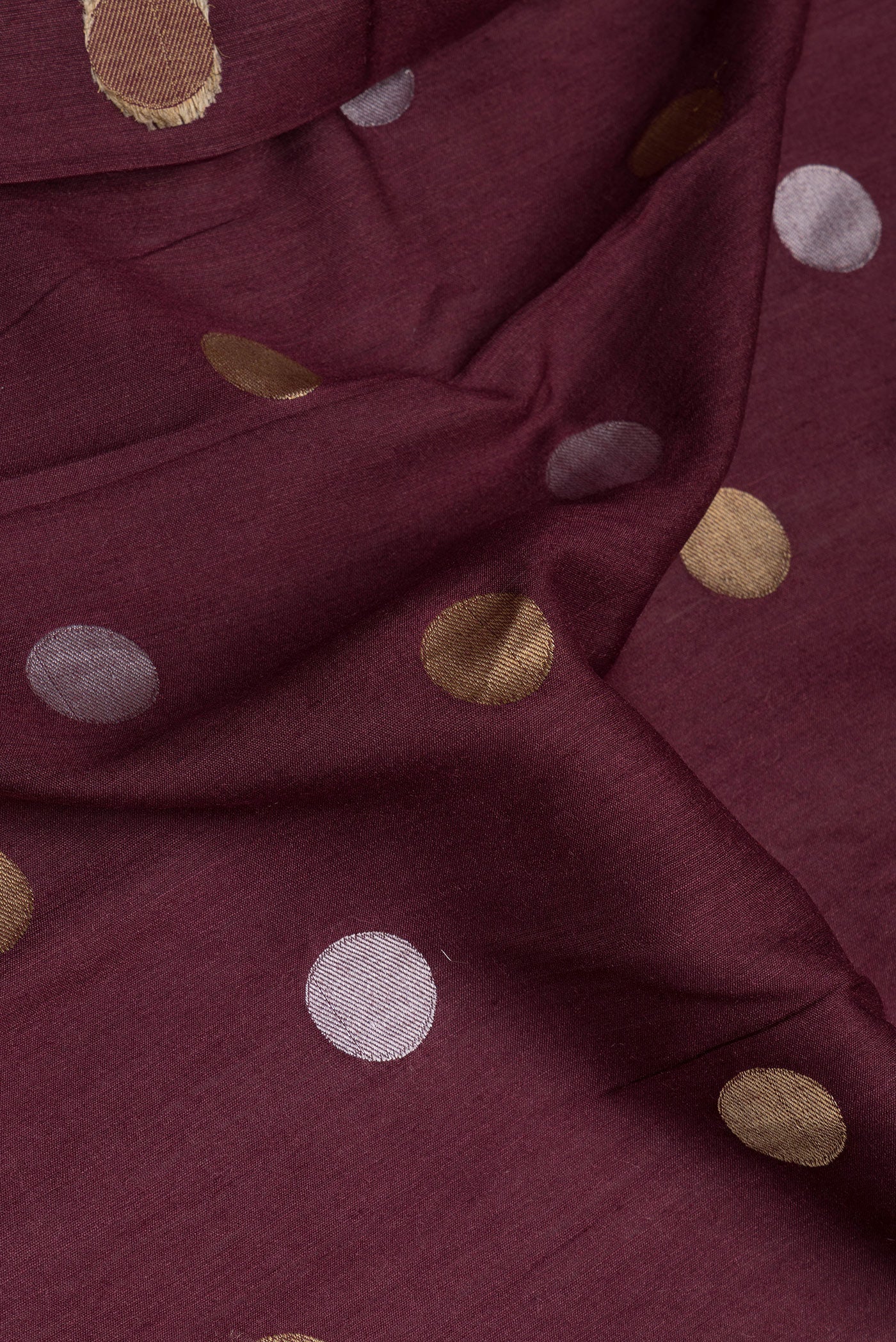 Close up of Burgundy Tussar Silk Saree with Polka Dots on the body and Zari Border.  displaying folds