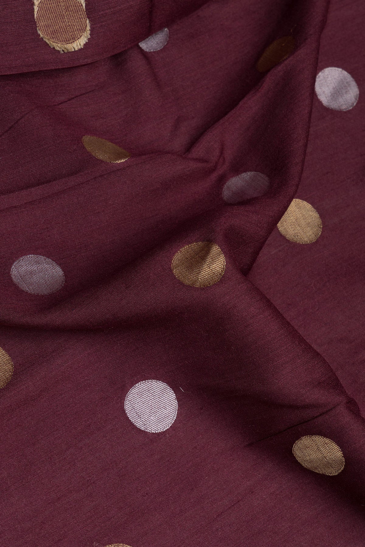Close up of Burgundy Tussar Silk Saree with Polka Dots on the body and Zari Border.  displaying folds