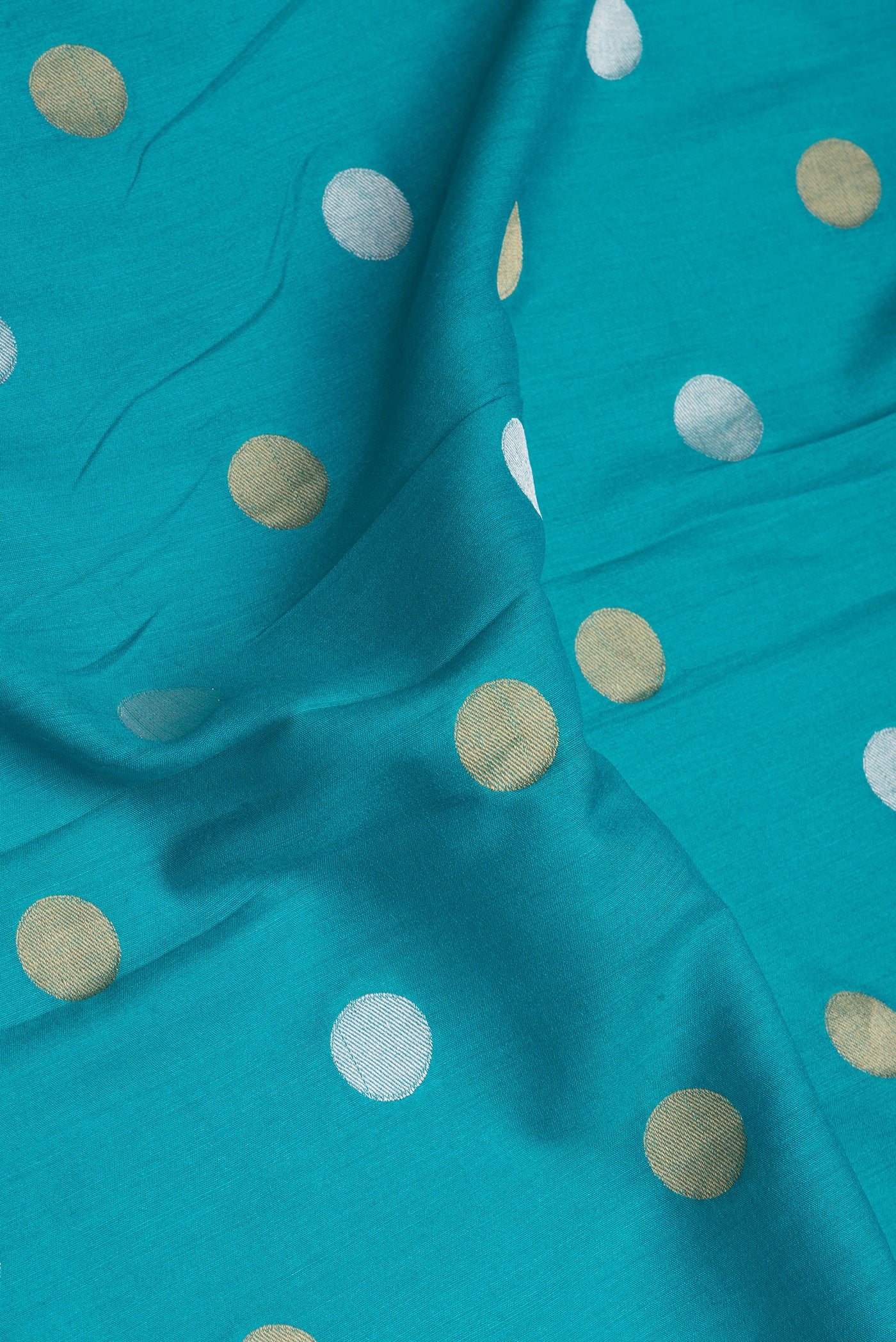 Close up of Sky Blue Tussar Silk Saree with Polka Dots on the body and Zari Border.  displaying folds