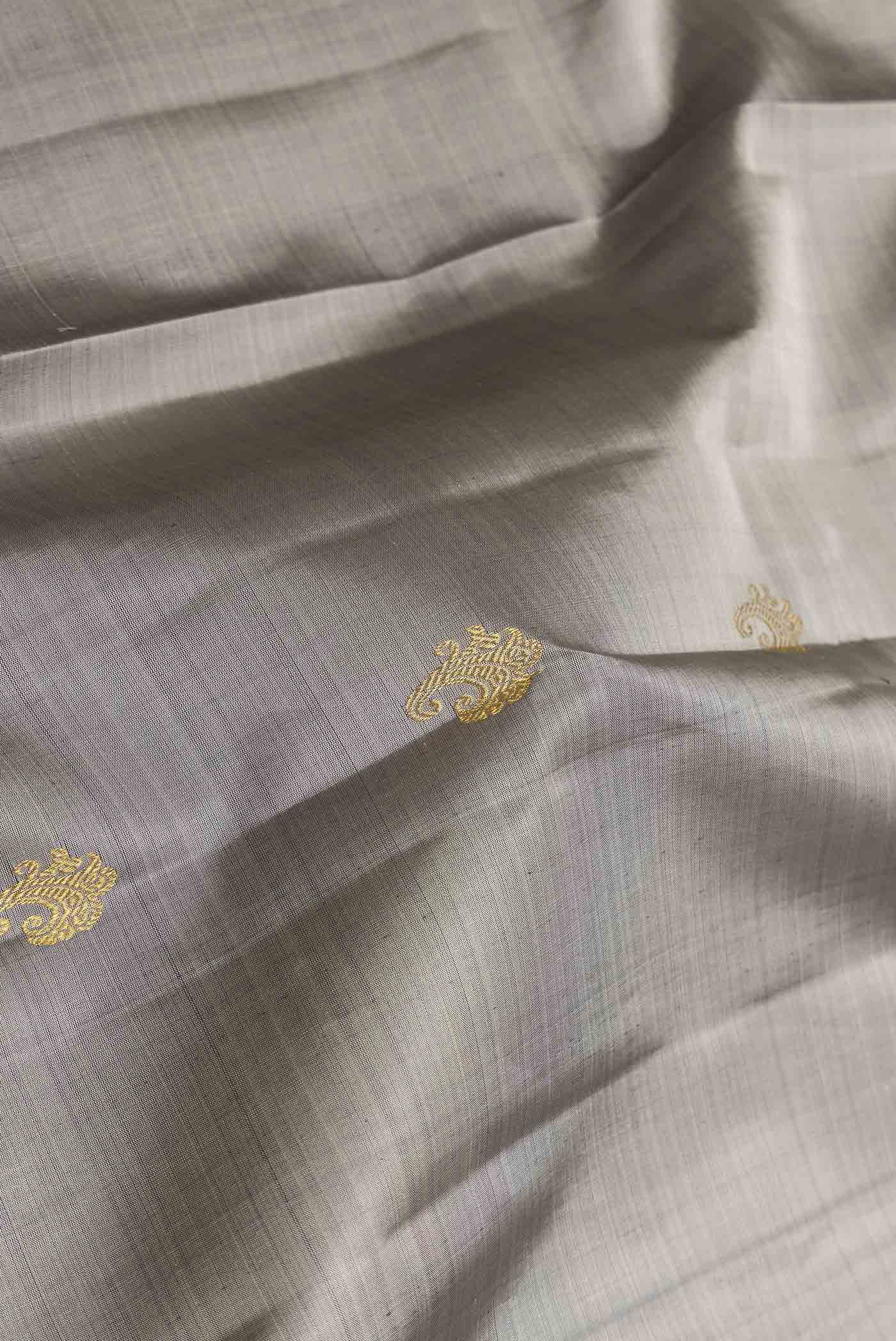 Close up of Grey Dual Tone Kanchipuram Saree with Zari Butta on the body and Zari Border displaying folds