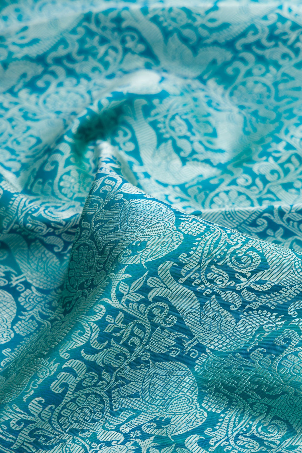 Close up of Pure Silk Pure Zari Peacock Blue Dual Tone Kanchipuram Saree with Jacquard design on the body and Zari Border.  displaying folds