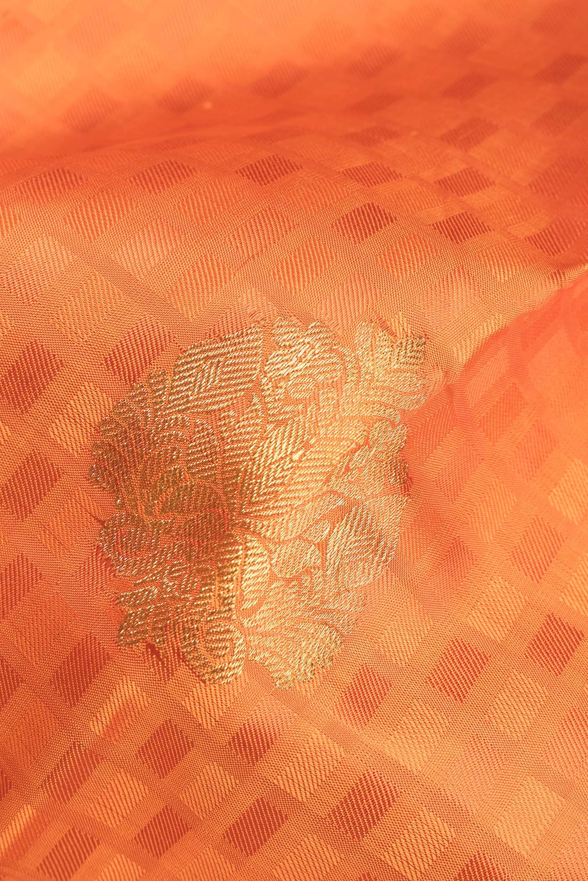 Close up of Pure Silk Orange Kanchipuram Saree with Jacquard With Zari Butta on the body and Zari Border.  displaying folds
