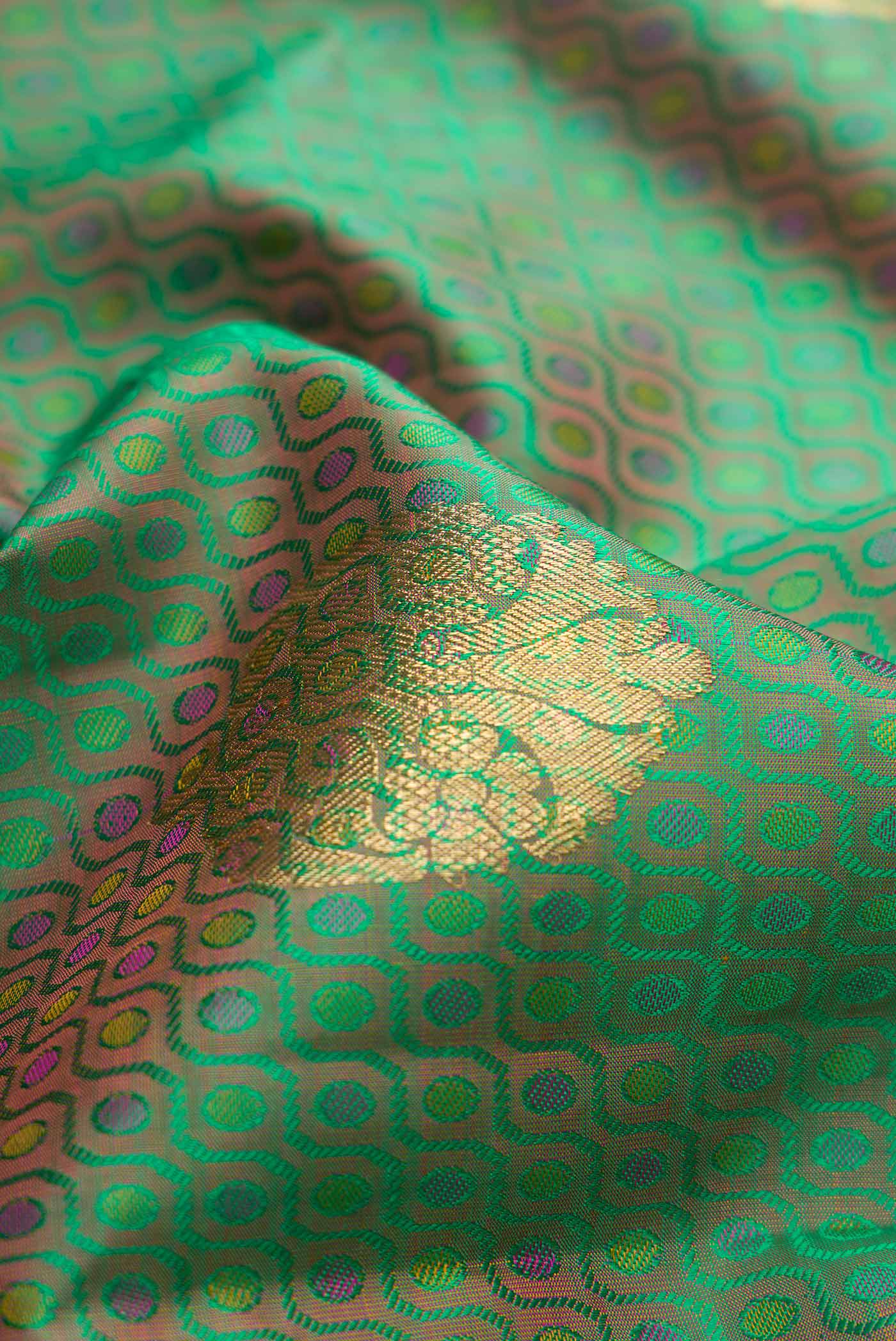 Close up of Pure Silk Pure Zari Green Dual Tone Kanchipuram Saree with Jacquard With Zari Butta on the body and Zari Border.  displaying folds