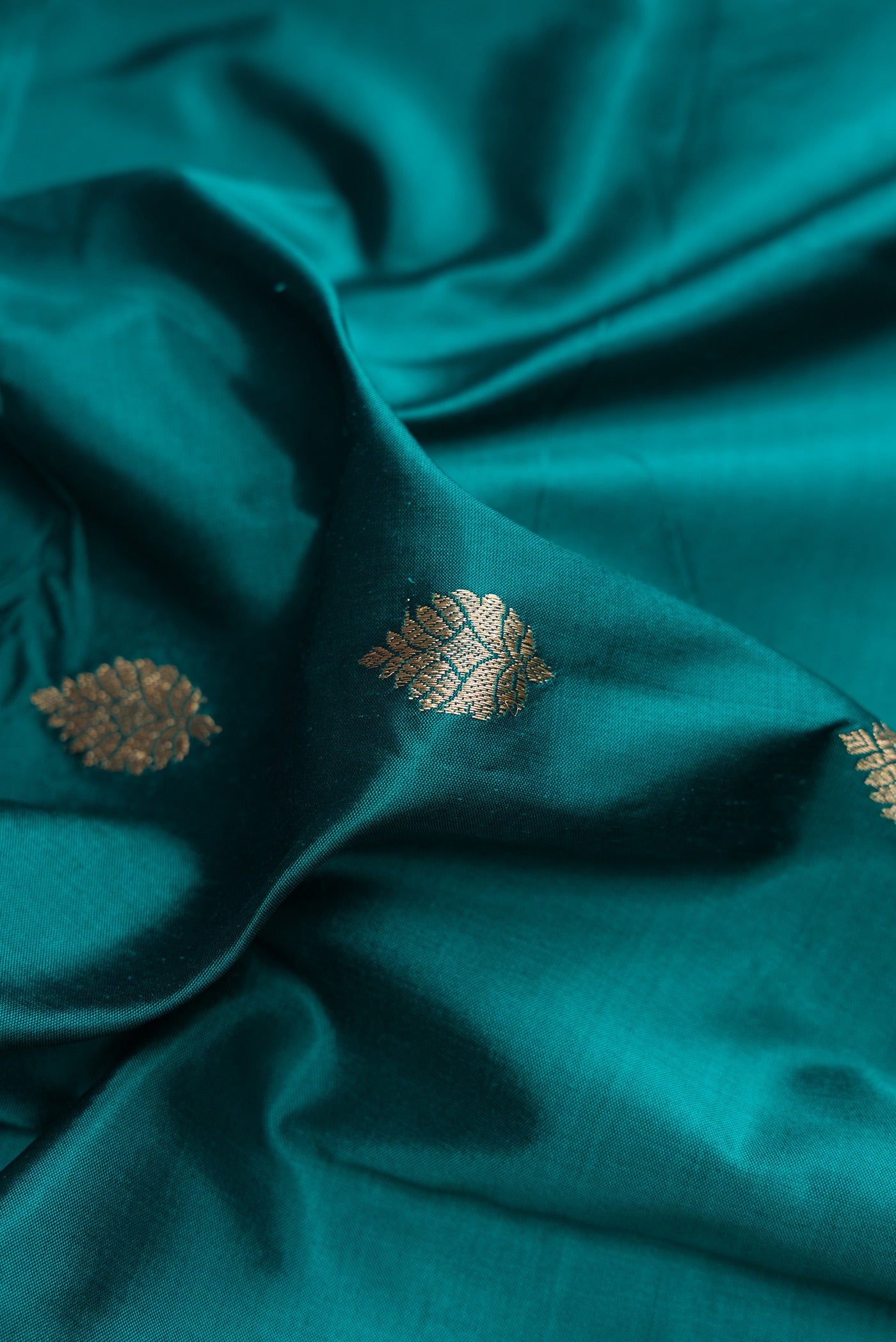 Close up of Peacock Blue Banarasi Silk Saree with Zari Butta on the body and Fancy Border.  displaying folds