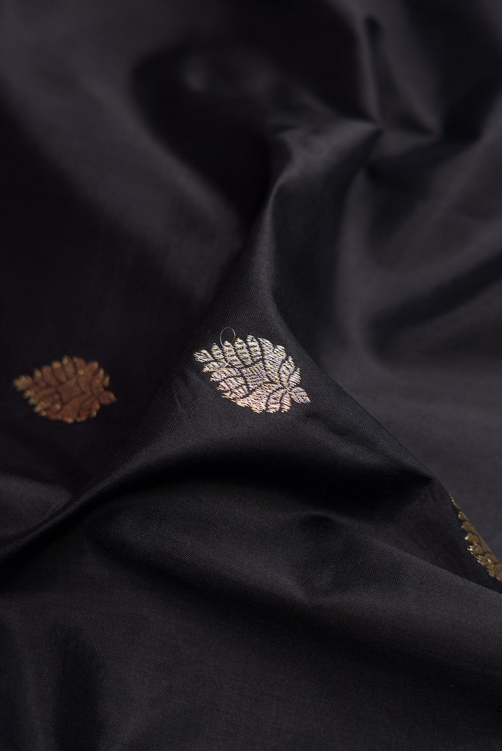 Close up of Black Banarasi Silk Saree with Zari Butta on the body and Fancy Border.  displaying folds