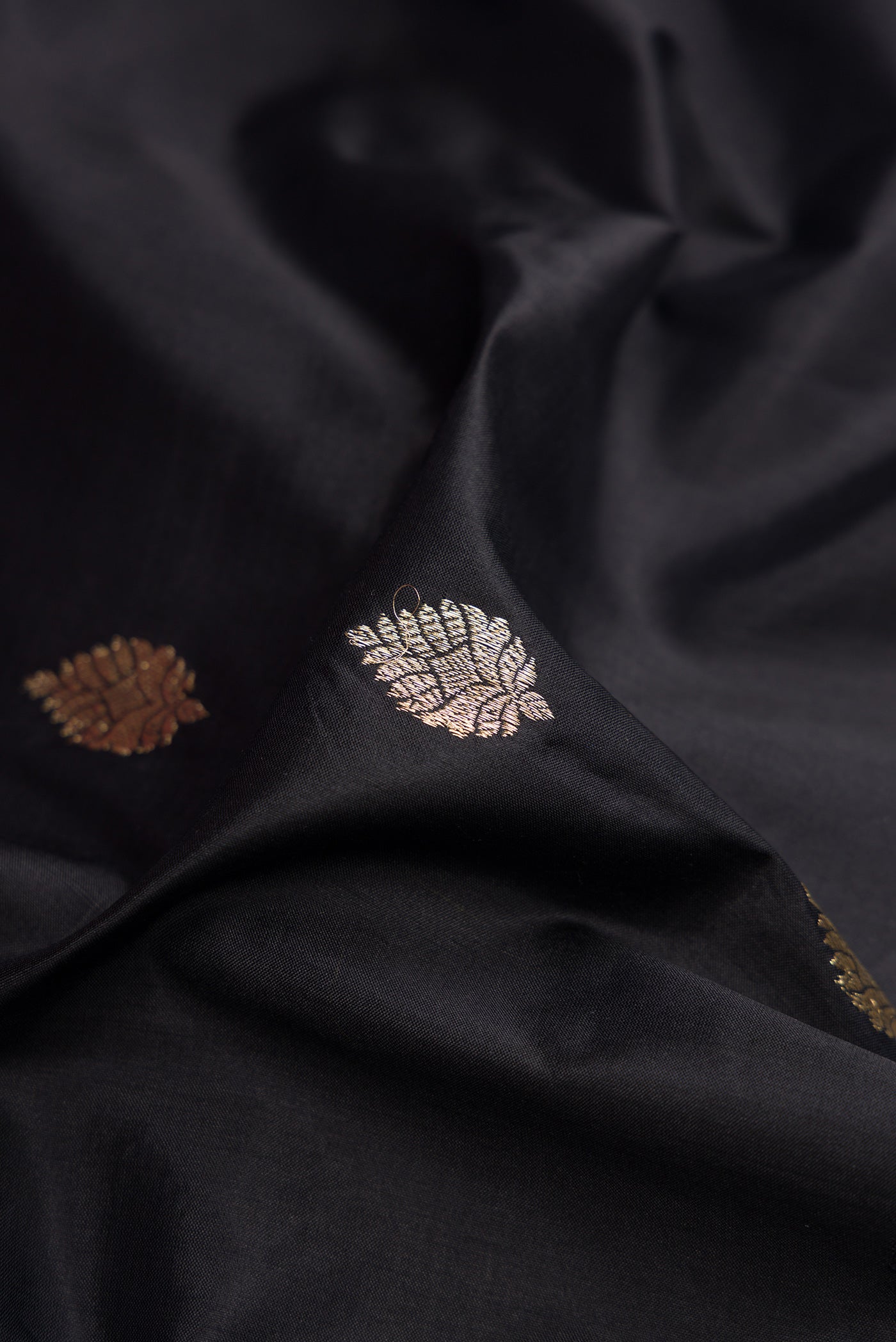Close up of Black Banarasi Silk Saree with Zari Butta on the body and Fancy Border.  displaying folds