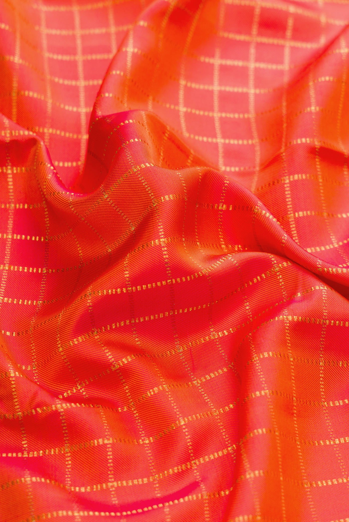 Close up of Orange Dual Tone Double Ikat Saree with Checked design on the body and Zari Border.  displaying folds