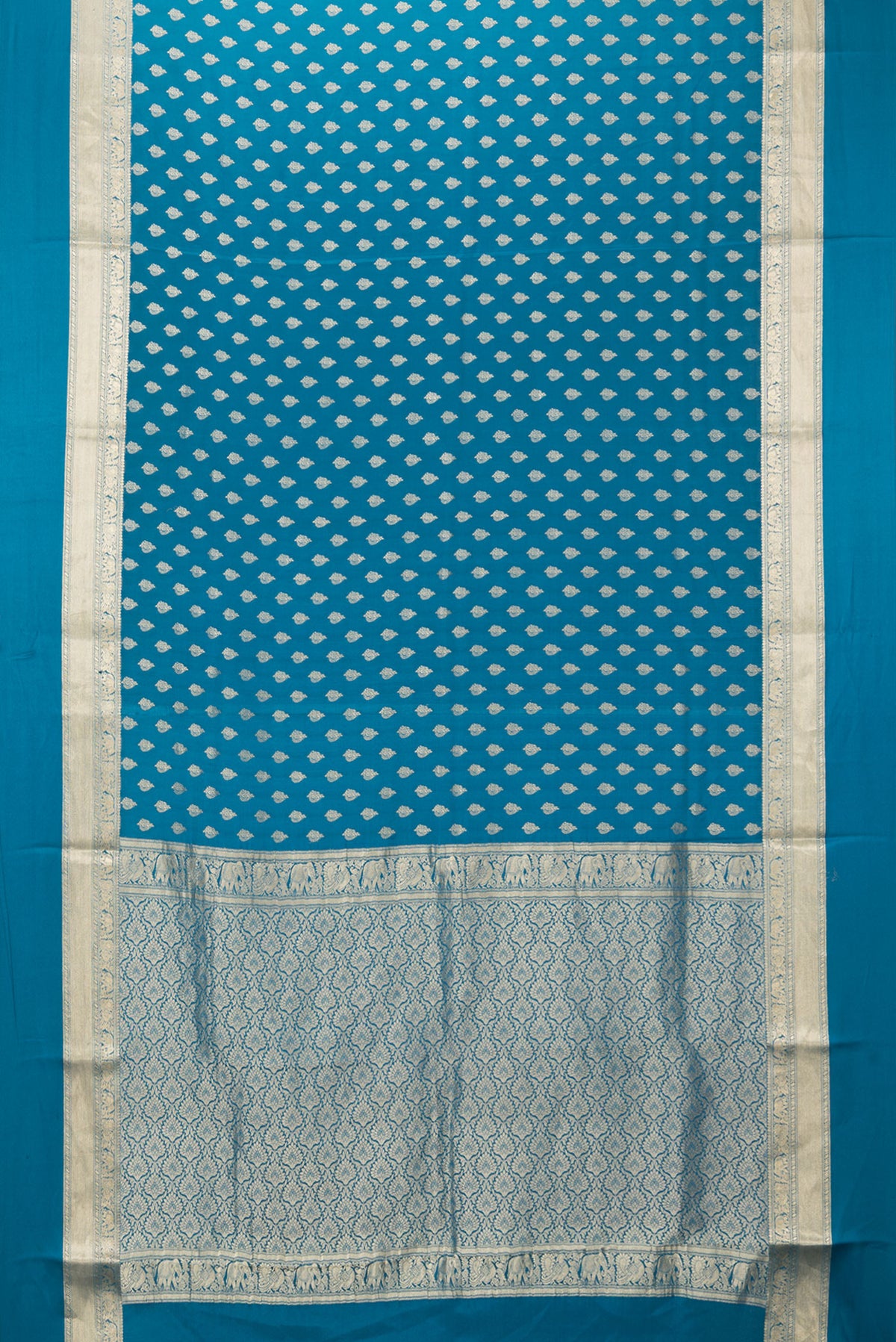 Flat view of Peacock Blue Mysore Crepe Saree with Zari Butta on the body and Zari Border. 
