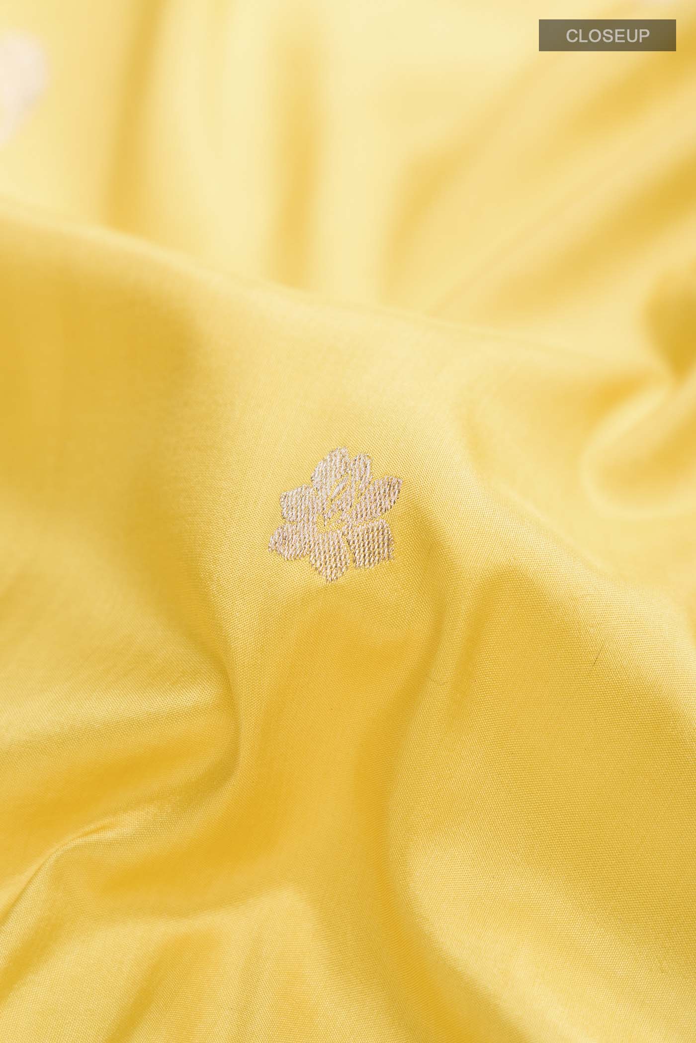 Close up of Yellow Banarasi Silk Saree with Zari Butta on the body and Zari Border displaying folds