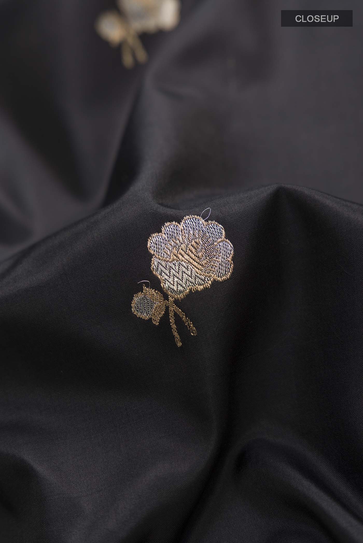Close up of Black Banarasi Katan Silk Saree with Zari Butta on the body and Zari Border displaying folds