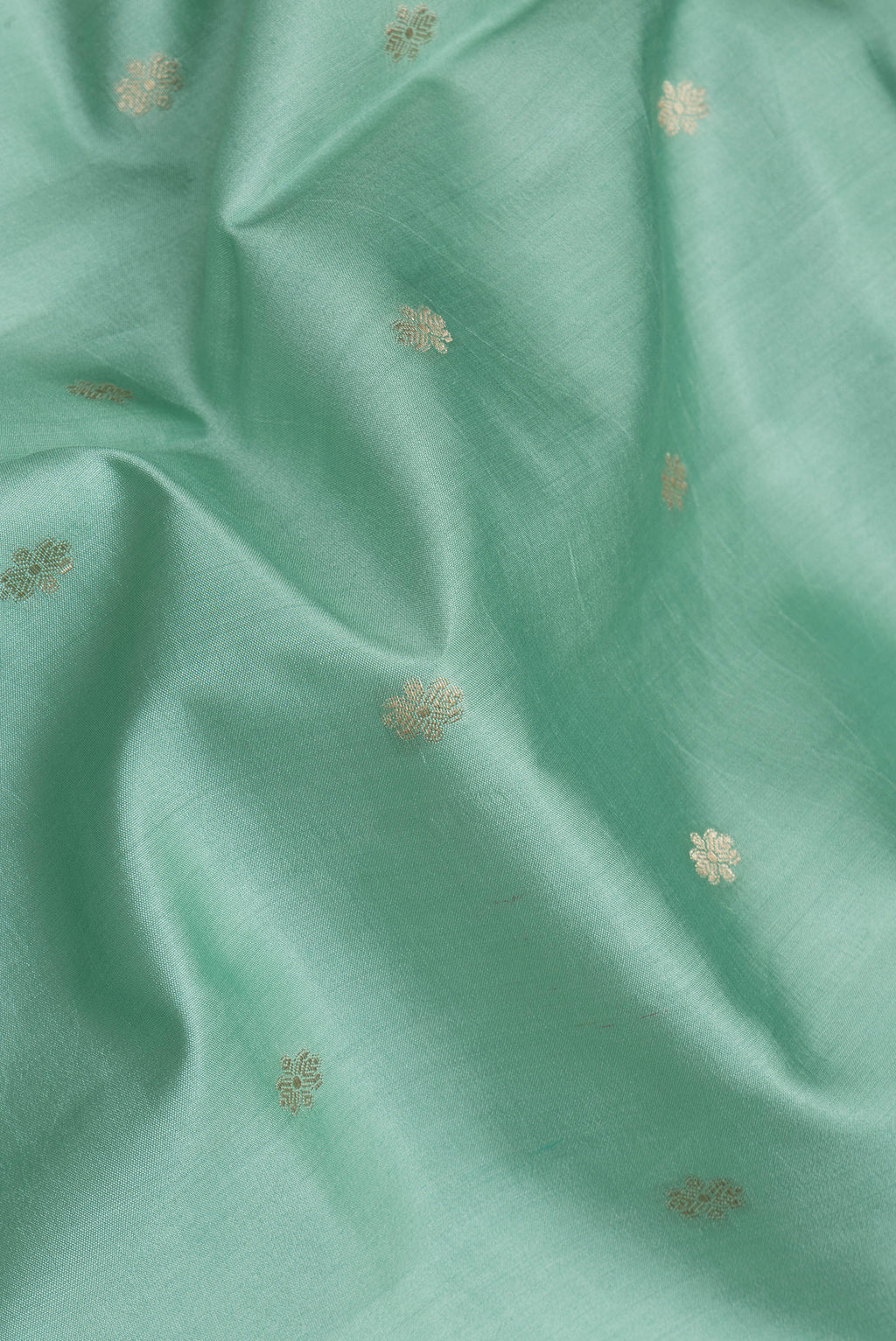 Close up of Sea Green Tussar Silk Saree with Zari Butta on the body and Zari Border.  displaying folds