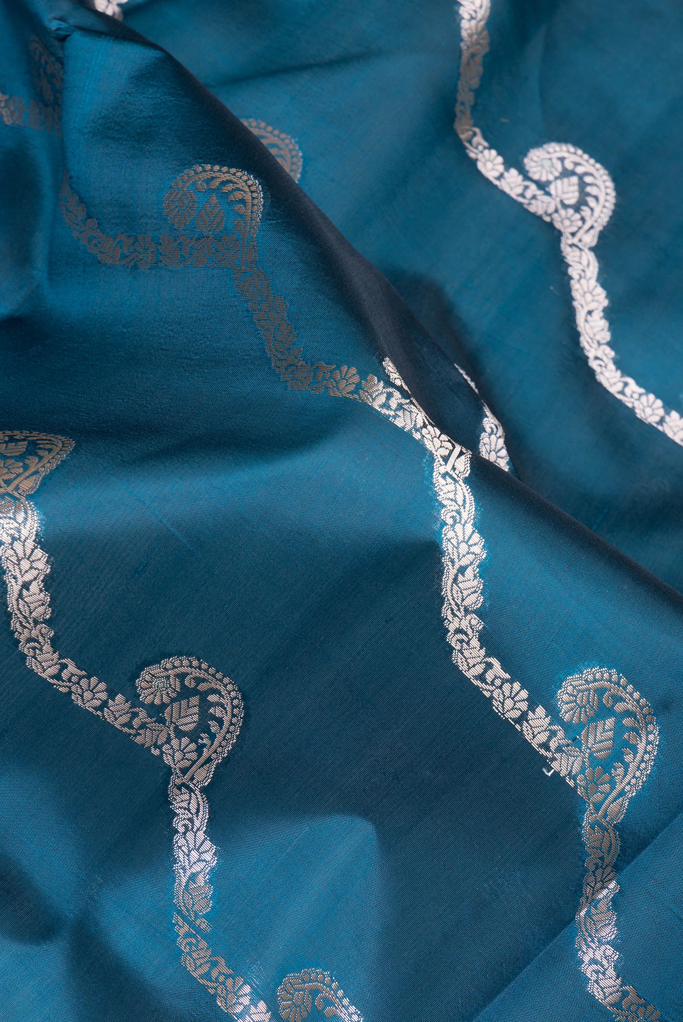 Close up of Peacock Blue Dual Tone Tussar Silk Saree with Zari Butta on the body and Fancy Border.  displaying folds