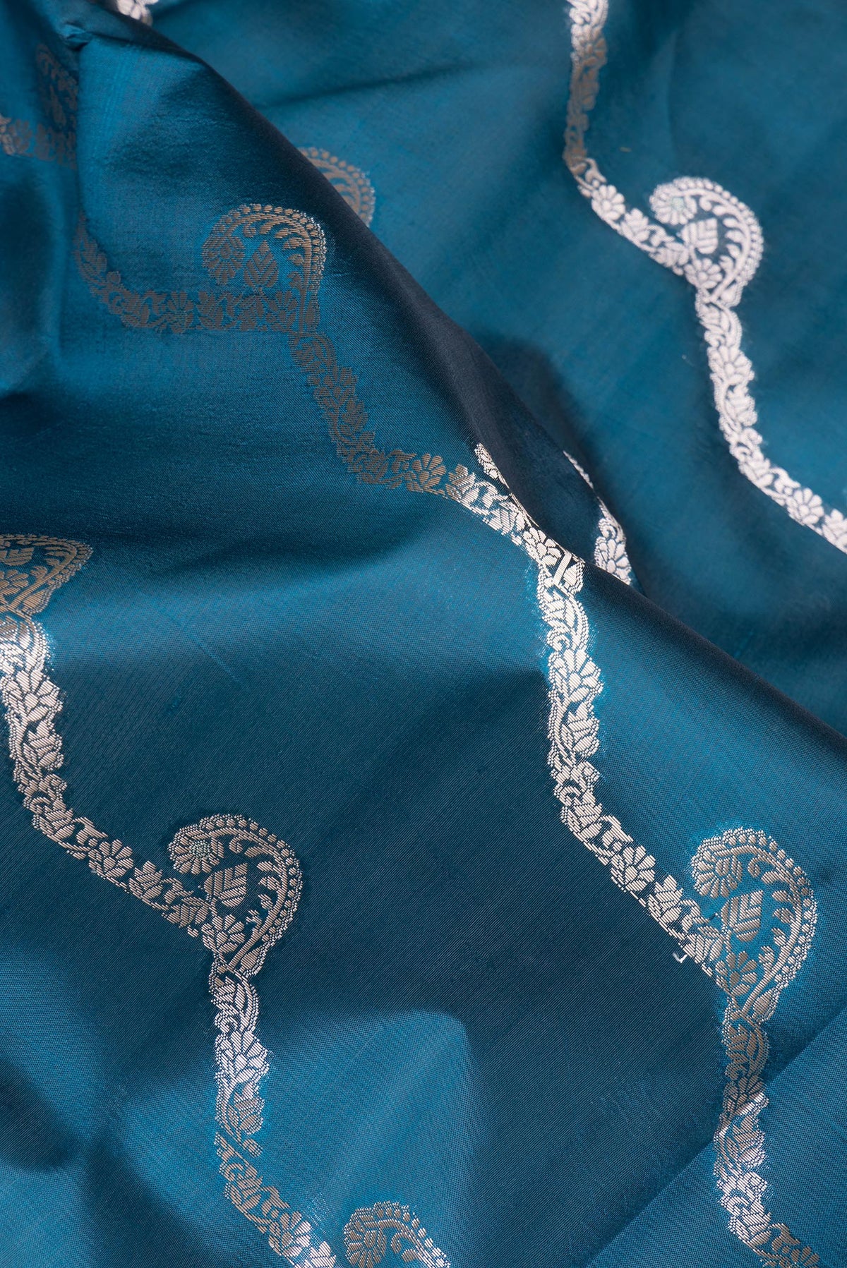 Close up of Peacock Blue Dual Tone Tussar Silk Saree with Zari Butta on the body and Fancy Border.  displaying folds