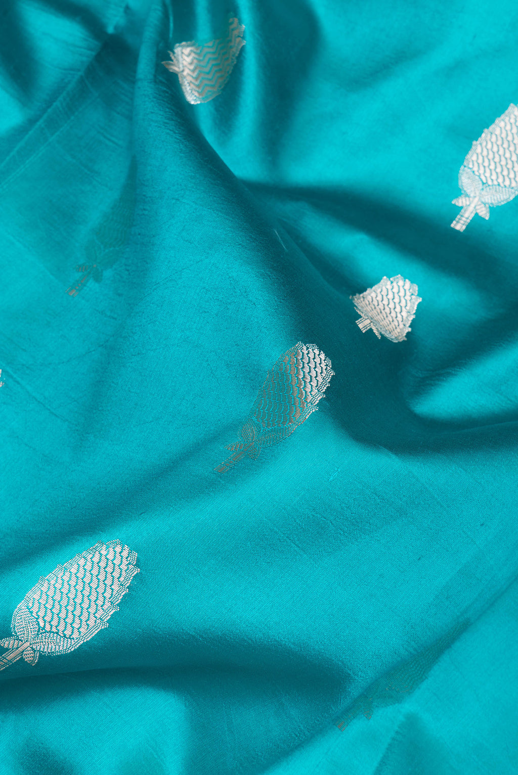 Close up of Sky Blue Tussar Silk Saree with Zari Butta on the body and Zari Border.  displaying folds