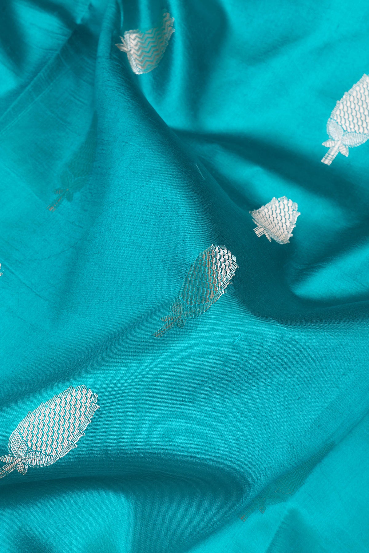 Close up of Sky Blue Tussar Silk Saree with Zari Butta on the body and Zari Border.  displaying folds