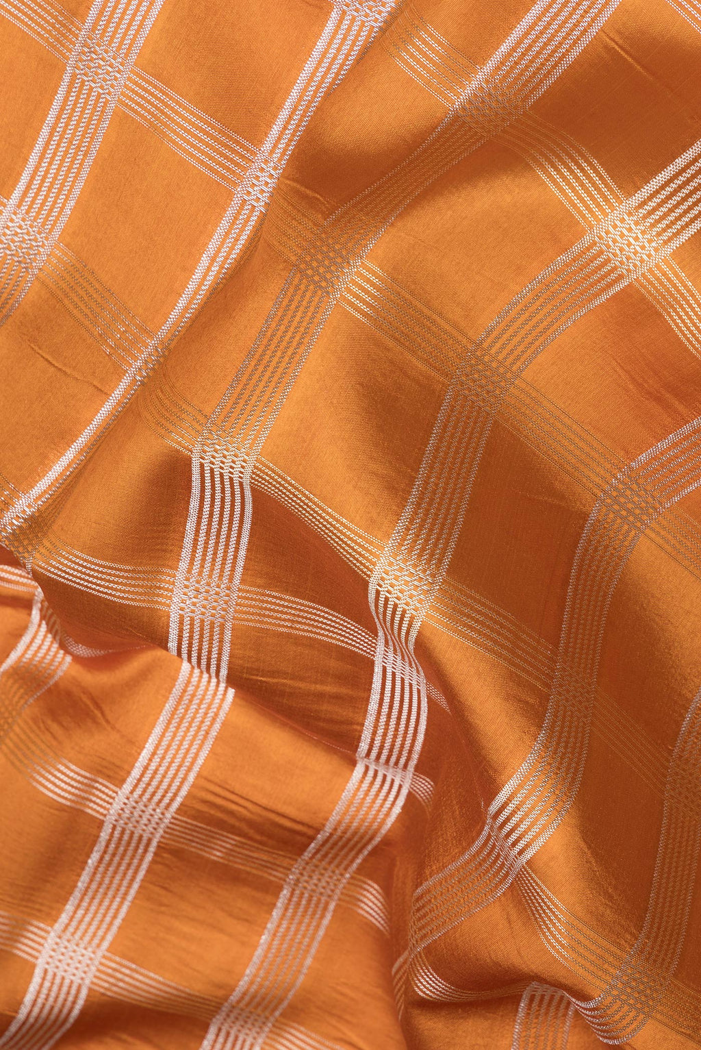 Close up of Brick Orange Dual Tone Tussar Silk Saree with Checked design on the body and Fancy Border.  displaying folds