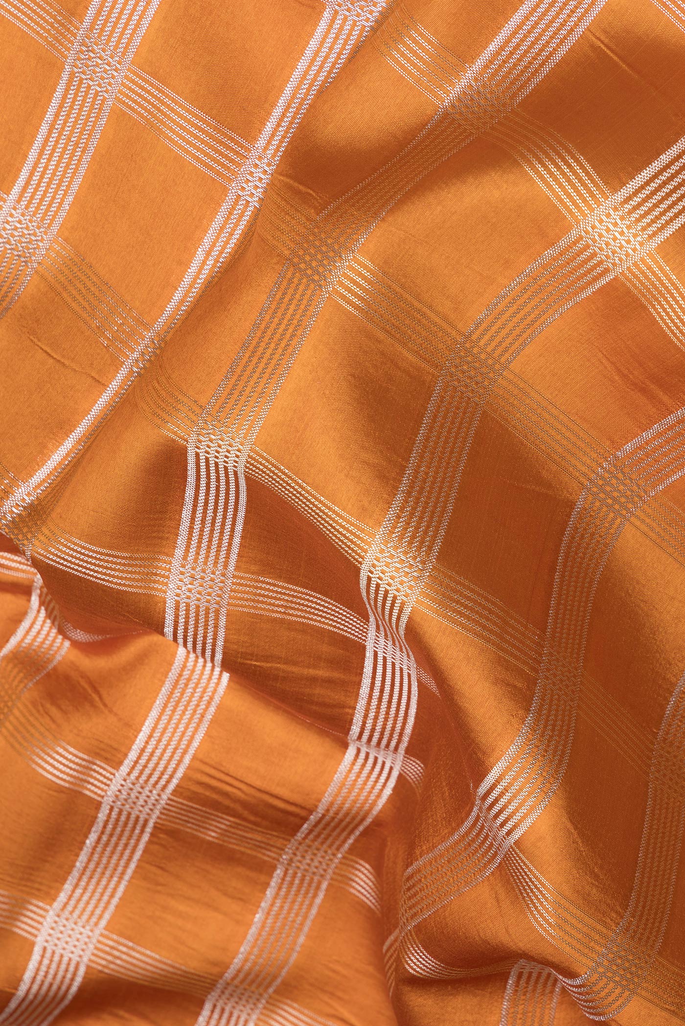 Close up of Brick Orange Dual Tone Tussar Silk Saree with Checked design on the body and Fancy Border.  displaying folds
